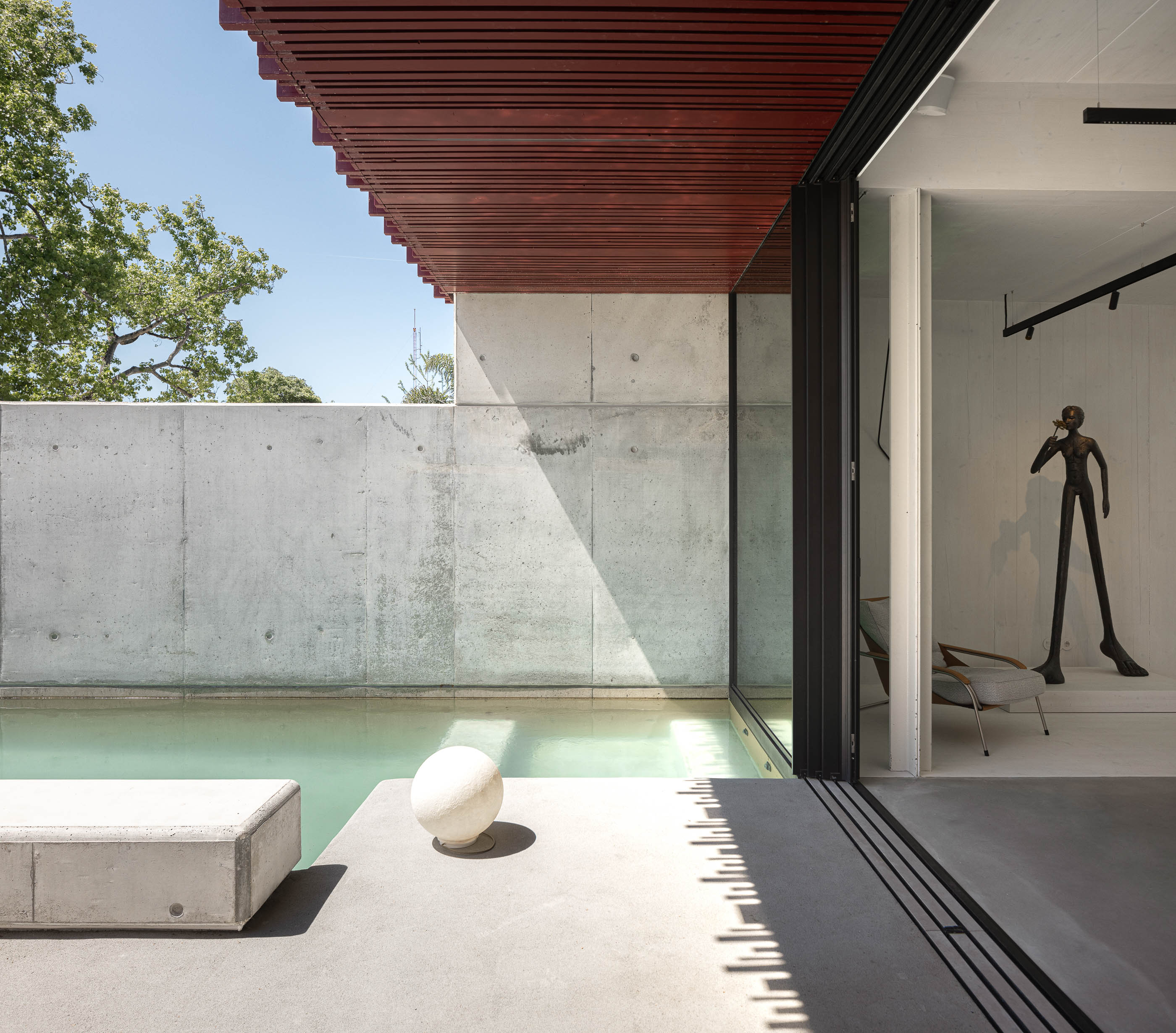 Exterior: Piscina com borda em betão, acesso ao interior da casa com porta deslizante e escultura. — Casa do Parque arquitetura Paulo Martins Arquitectura e Design em Aveiro