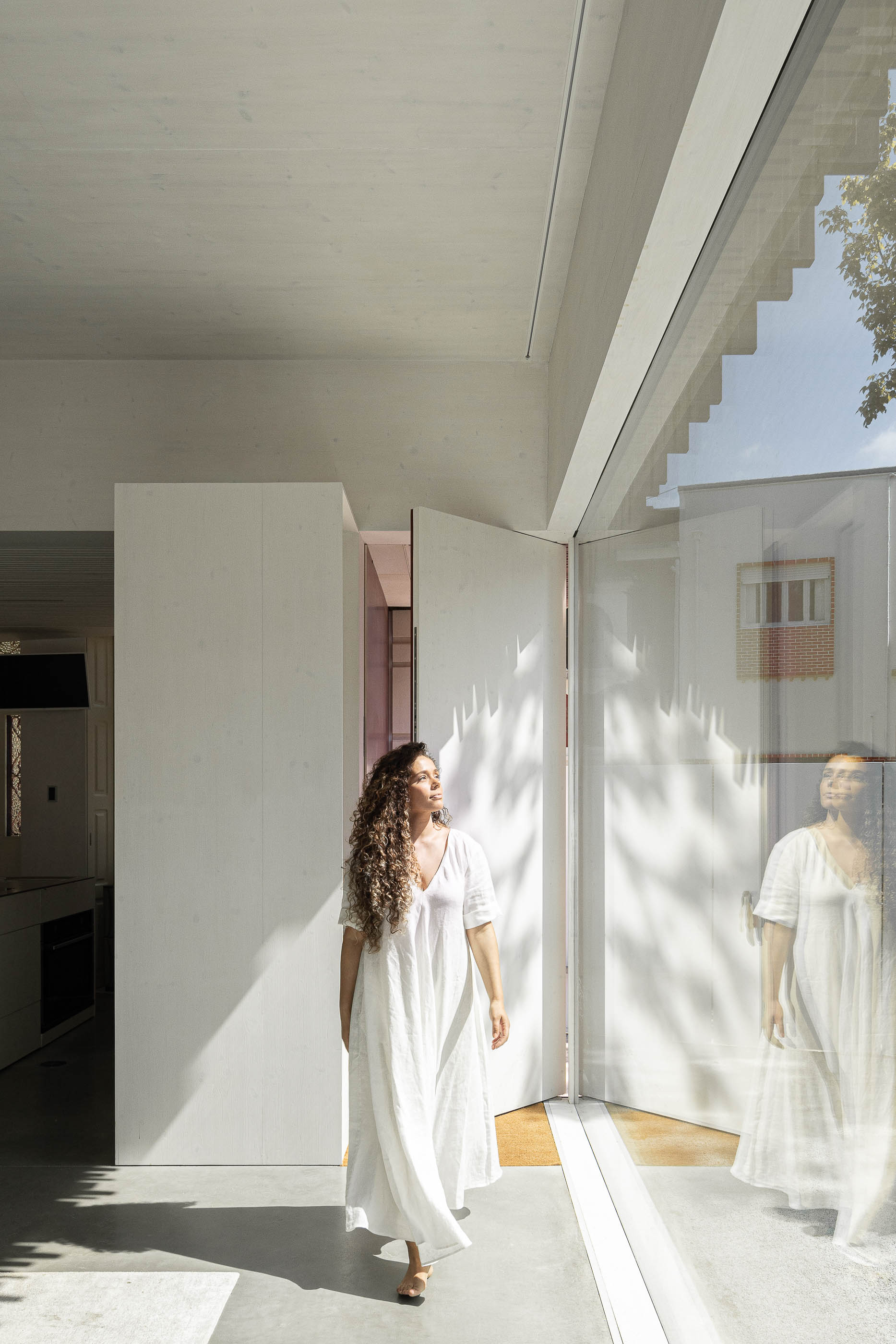 Cozinha: Interior com porta de correr aberta, pavimento em cimento afagado e reflexo no vidro. — Casa do Parque arquitetura Paulo Martins Arquitectura e Design em Aveiro