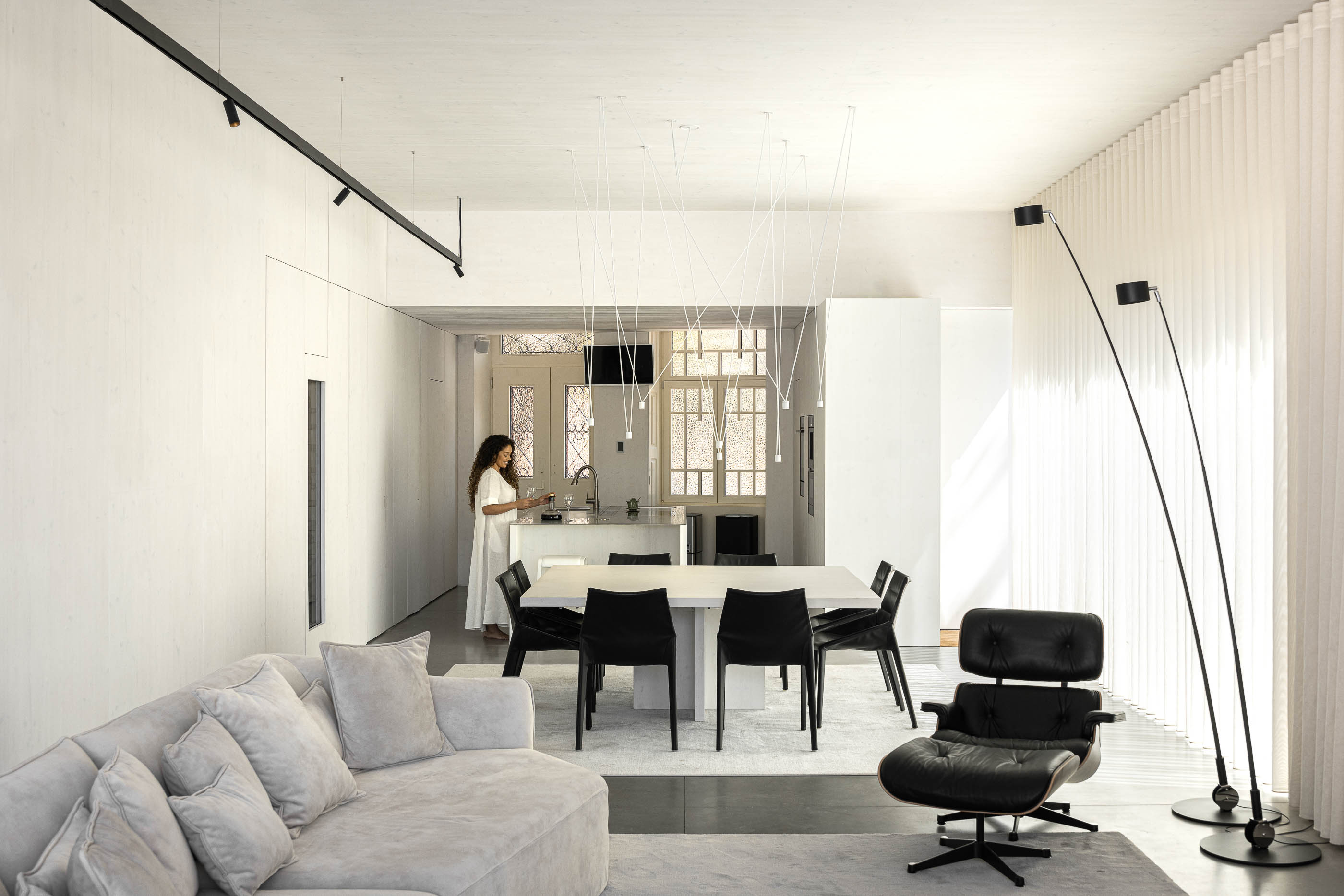 Sala de estar: Espaço amplo com sofá, mesa de jantar, cadeiras pretas e candeeiros modernos. — Casa do Parque arquitetura Paulo Martins Arquitectura e Design em Aveiro
