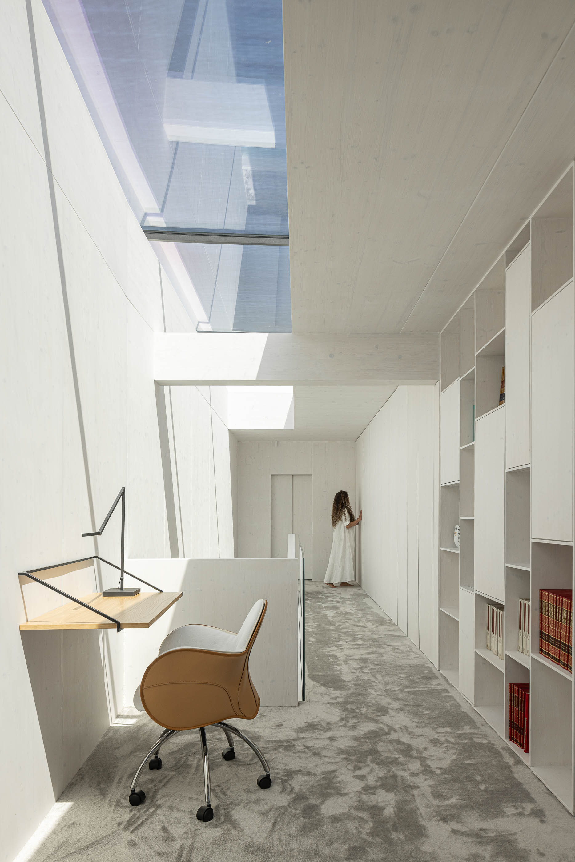 Escritório: Corredor com escritório, estantes brancas, alcatifa cinzenta e iluminação natural. — Casa do Parque arquitetura Paulo Martins Arquitectura e Design em Aveiro