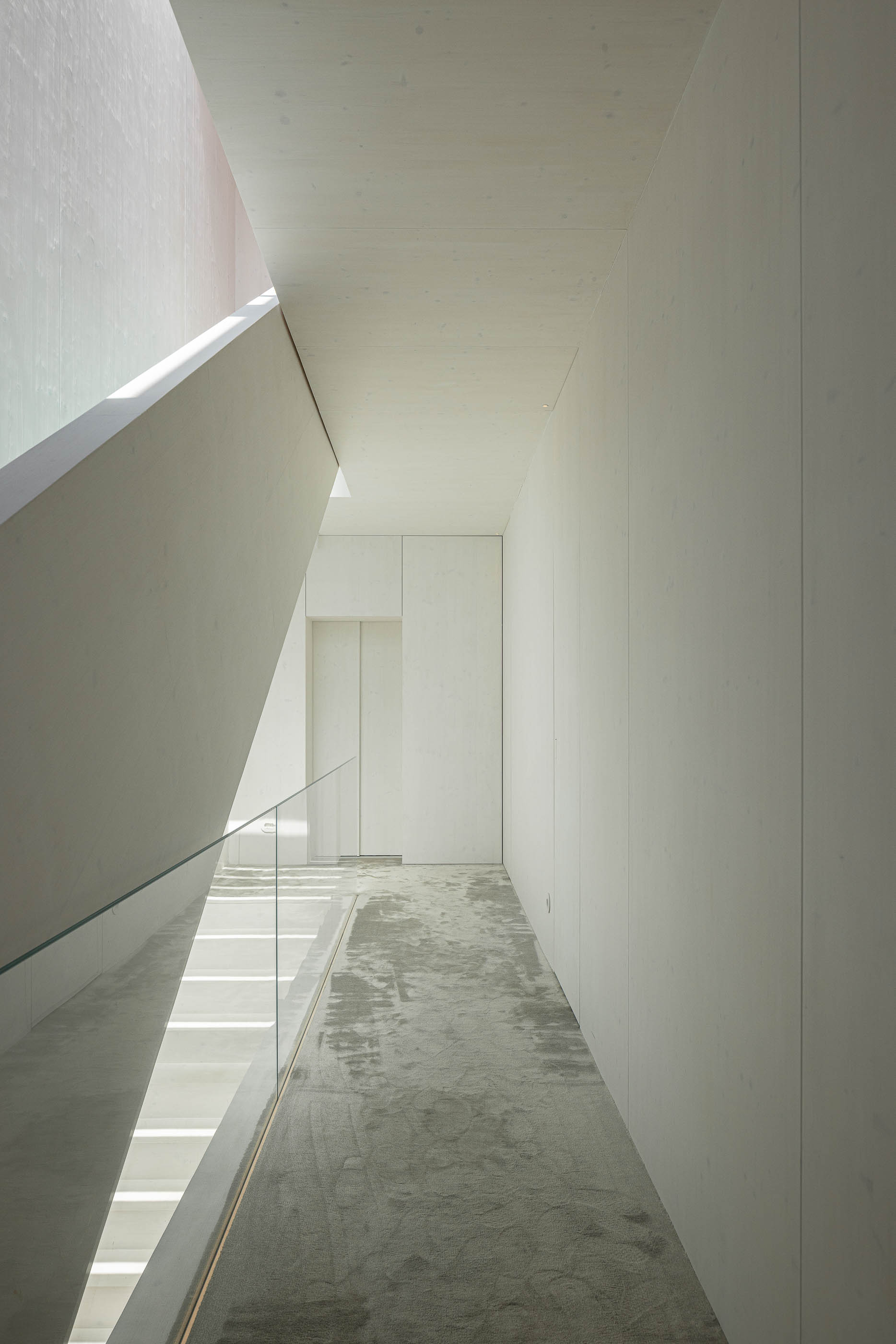 Corredor: Corredor com alcatifa cinzenta, escadas com degraus em vidro e paredes brancas. — Casa do Parque arquitetura Paulo Martins Arquitectura e Design em Aveiro