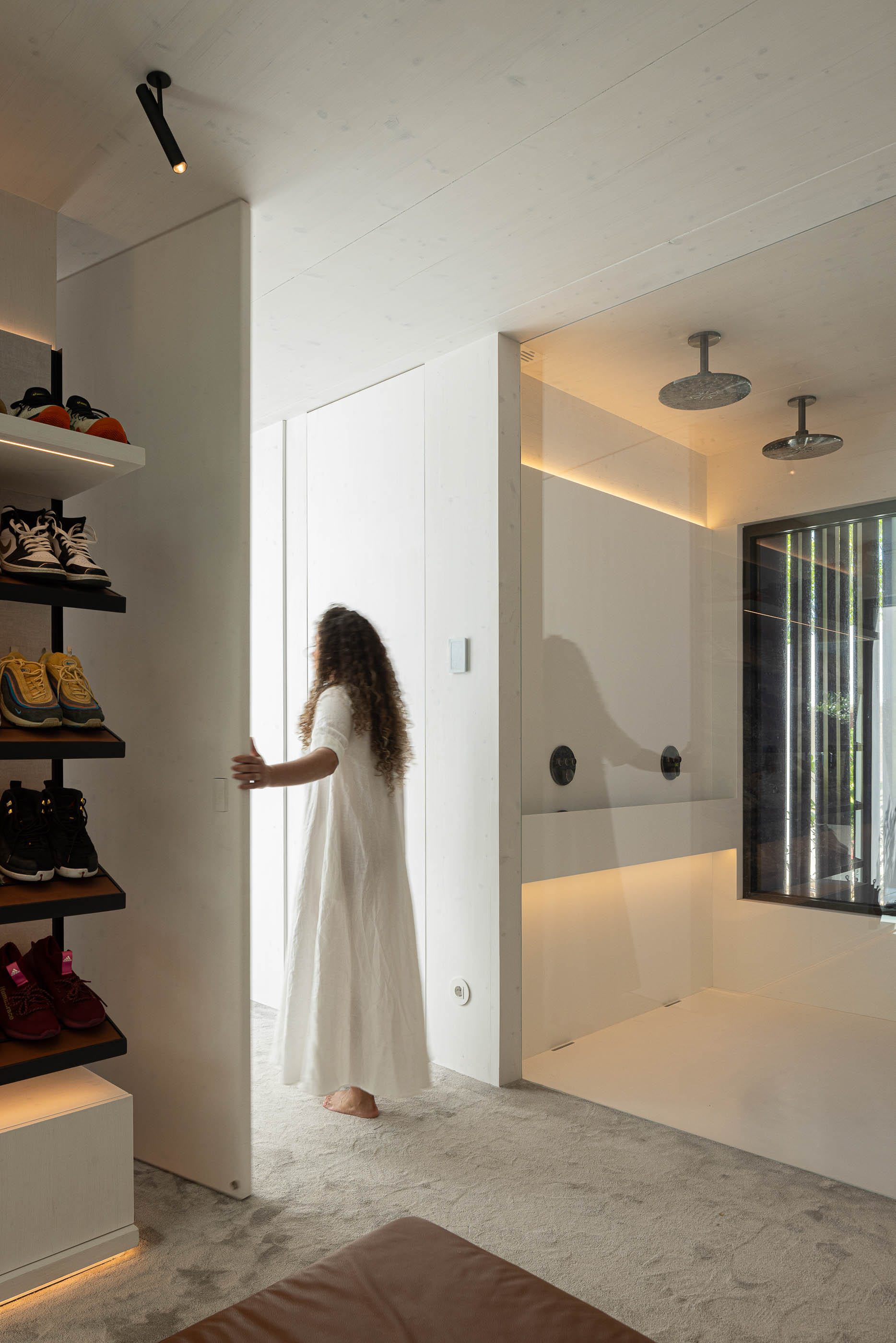 Quarto: Acesso à casa de banho e closet, com prateleiras para sapatos iluminadas. — Casa do Parque arquitetura Paulo Martins Arquitectura e Design em Aveiro