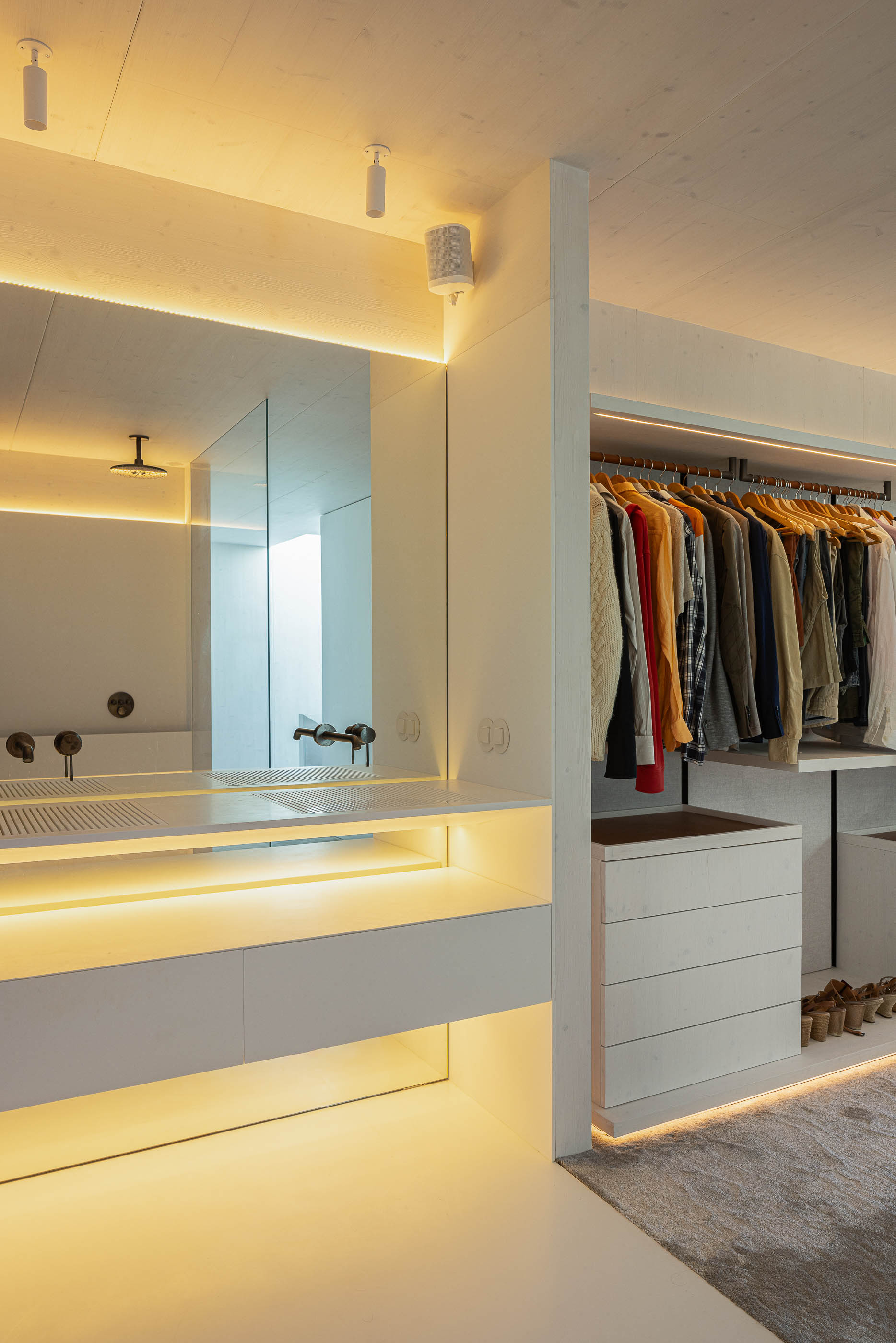 Casa de banho: Lavatório duplo com iluminação embutida, espelho amplo e closet adjacente. — Casa do Parque arquitetura Paulo Martins Arquitectura e Design em Aveiro