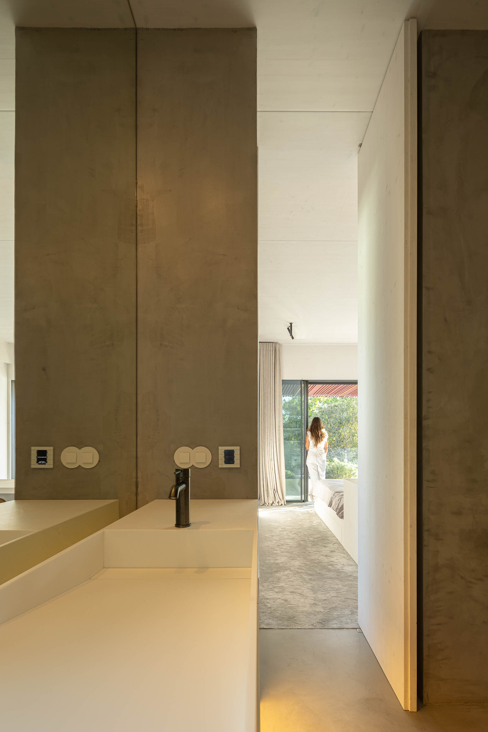 Casa de banho: Lavatório branco com torneira preta, espelho amplo e acesso ao quarto. — Casa do Parque arquitetura Paulo Martins Arquitectura e Design em Aveiro