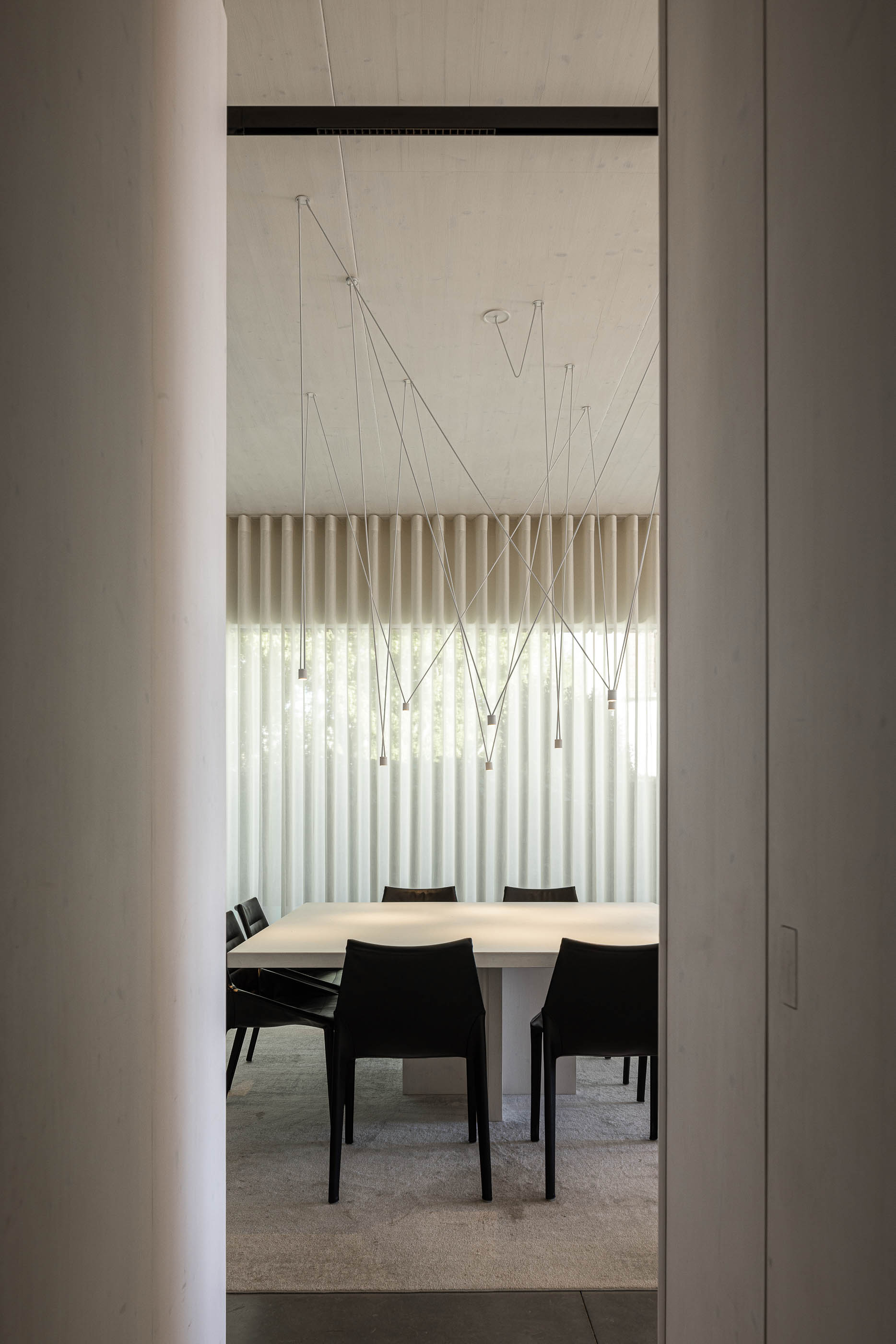 Sala de jantar: Mesa de jantar branca com cadeiras pretas, candeeiros suspensos e cortinas brancas. — Casa do Parque arquitetura Paulo Martins Arquitectura e Design em Aveiro