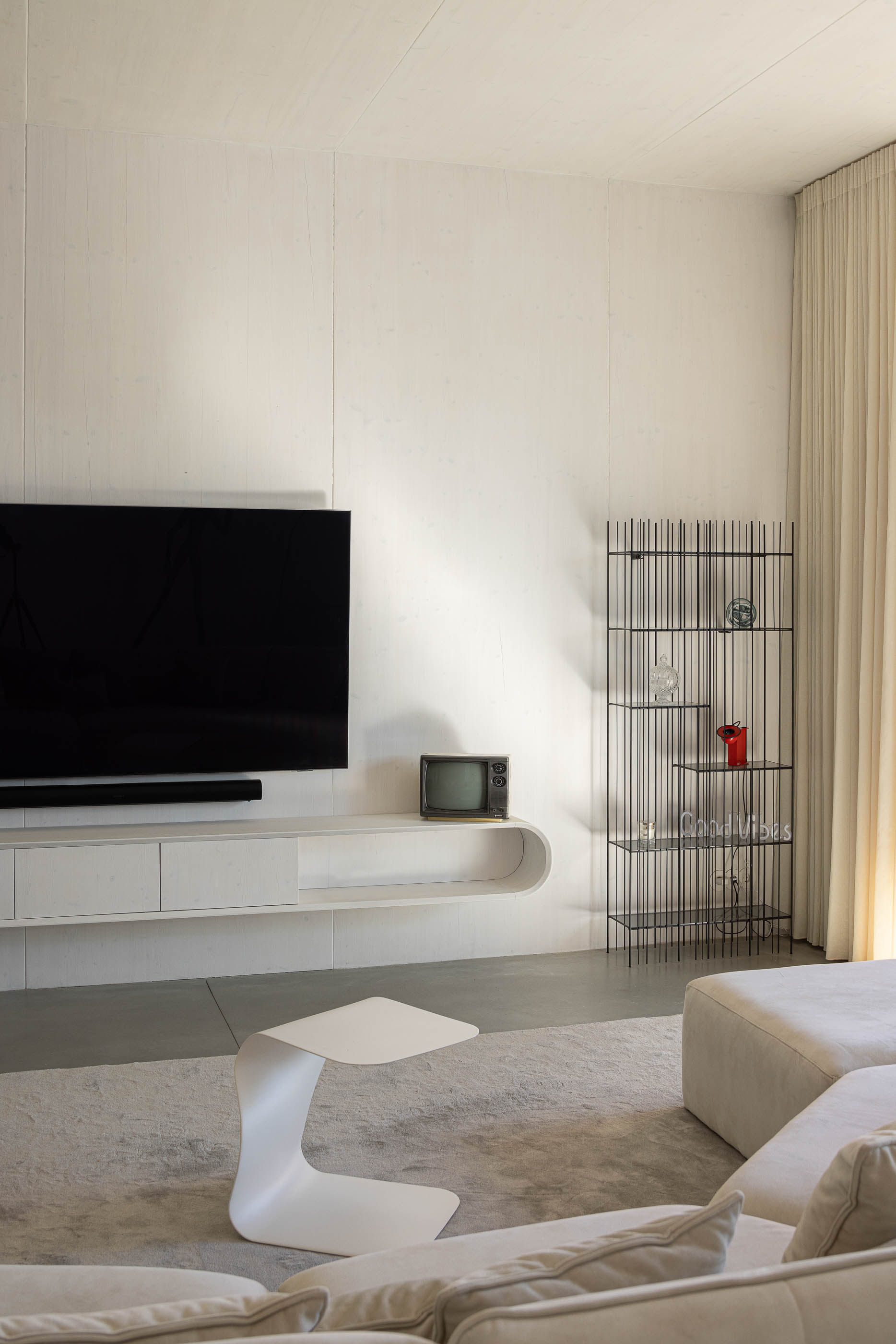 Sala de estar: Sofá bege, televisão, estante metálica e alcatifa cinzenta. — Casa do Parque arquitetura Paulo Martins Arquitectura e Design em Aveiro
