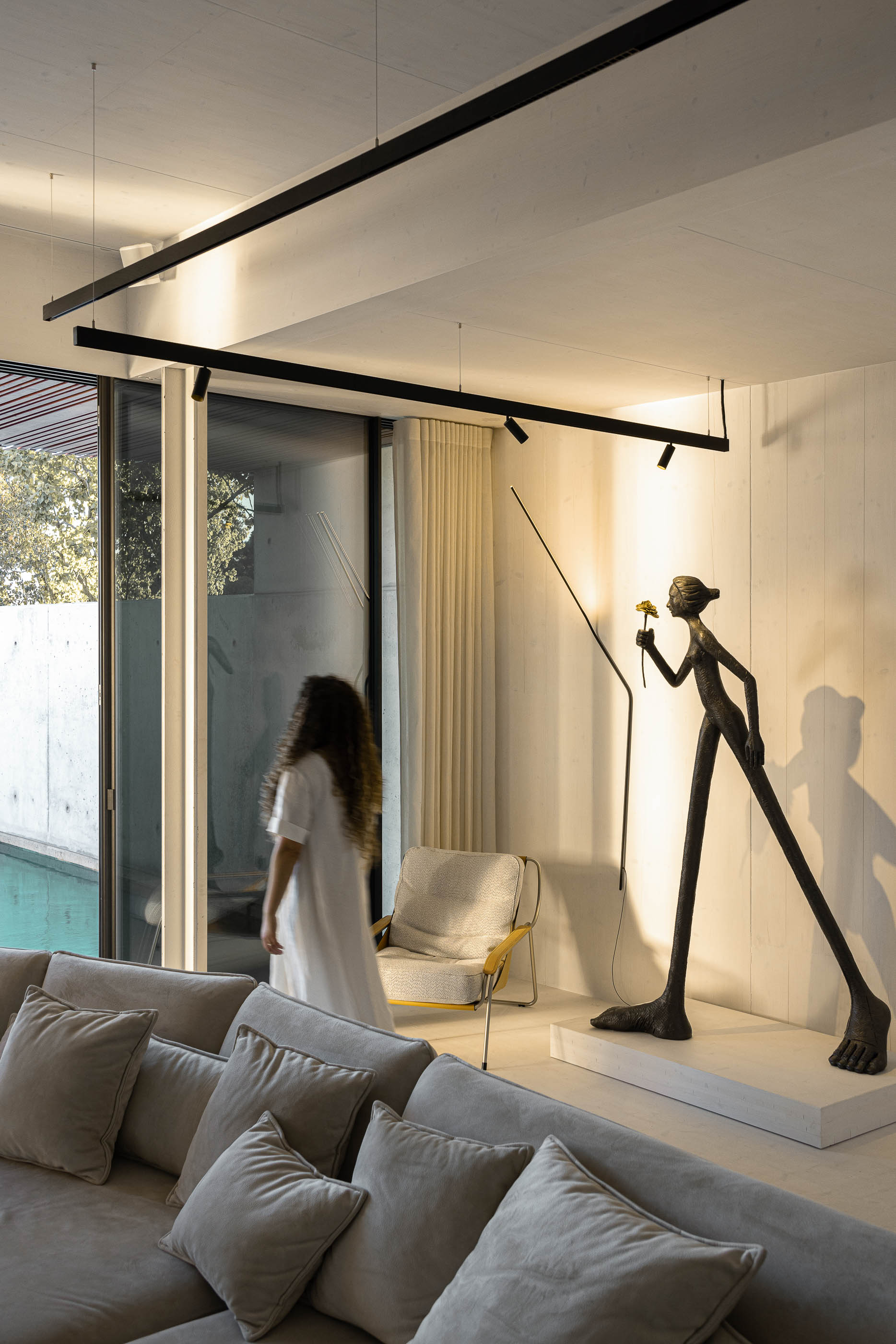 Sala de estar: Sofá bege, escultura moderna e vista para a piscina através da porta de correr. — Casa do Parque arquitetura Paulo Martins Arquitectura e Design em Aveiro