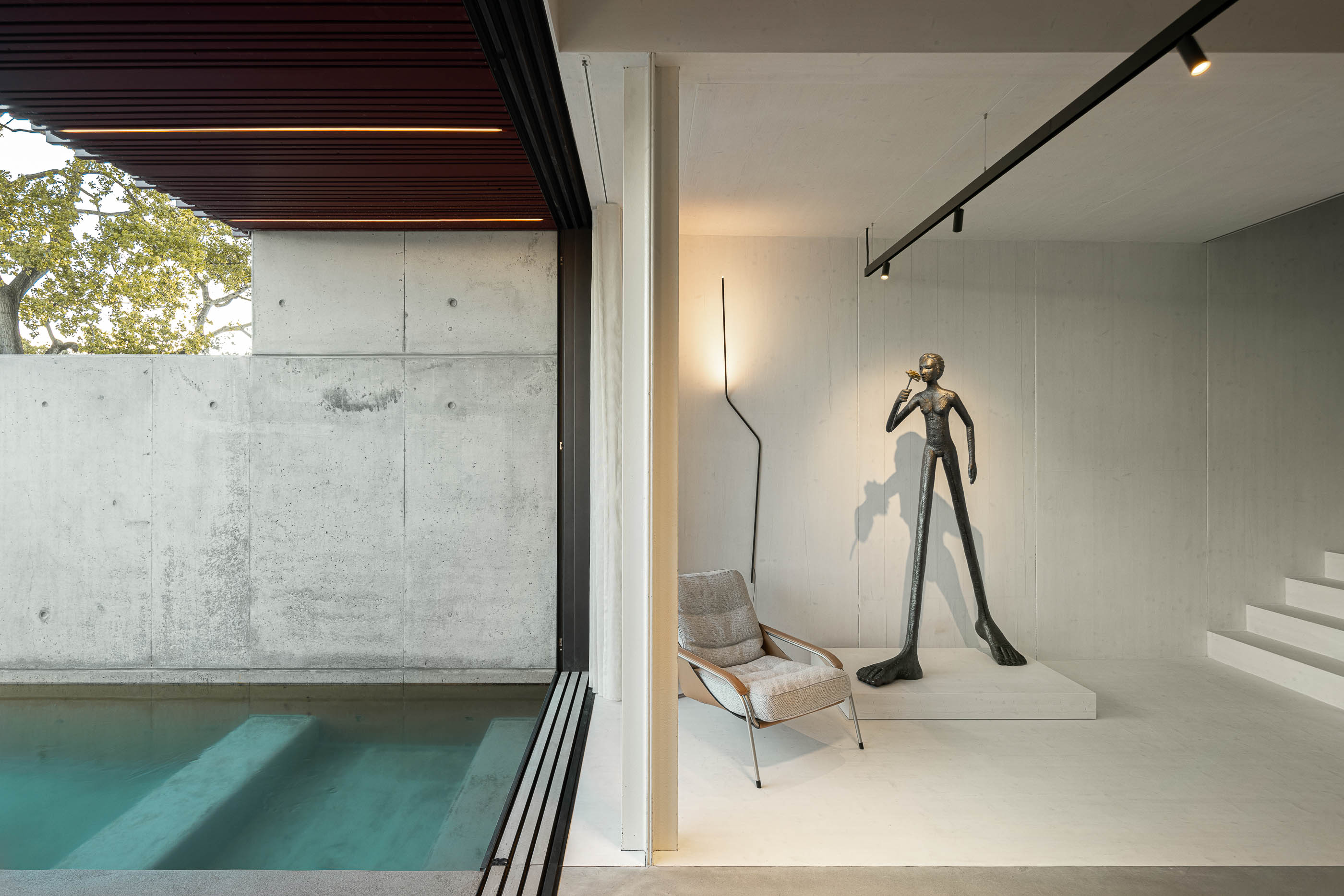Sala de estar: Escultura moderna, poltrona e vista para a piscina através da porta de correr. — Casa do Parque arquitetura Paulo Martins Arquitectura e Design em Aveiro
