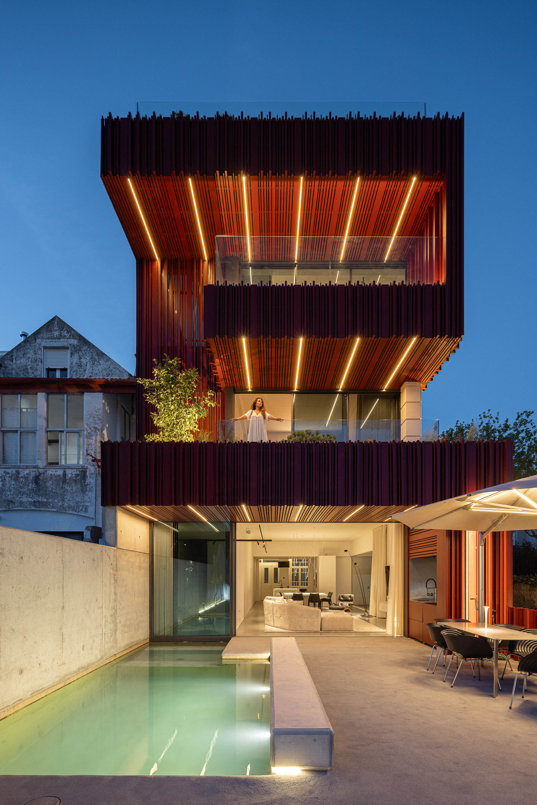 Exterior: Fachada posterior da casa iluminada, com piscina, zona de refeições e sala de estar. — Casa do Parque arquitetura Paulo Martins Arquitectura e Design em Aveiro