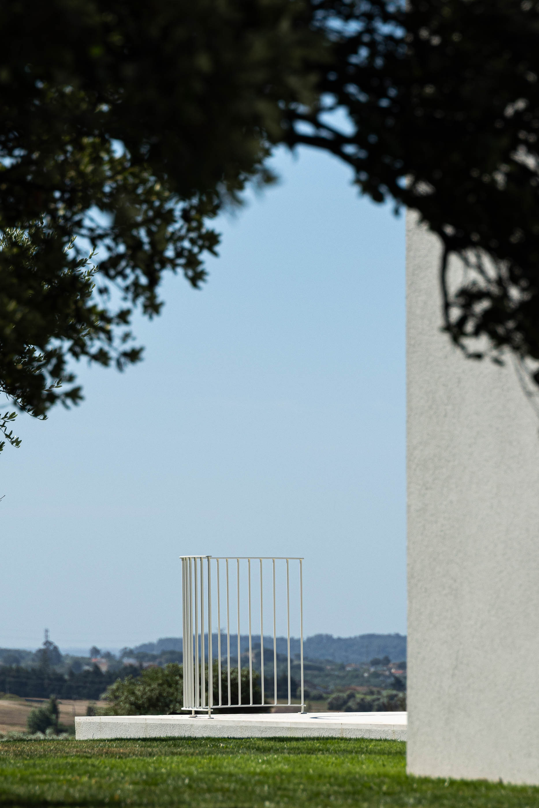 Exterior: Varanda com grade metálica branca, relvado e vista para a paisagem rural. — Casa na Romeira arquitetura dp arquitectos em Santarém