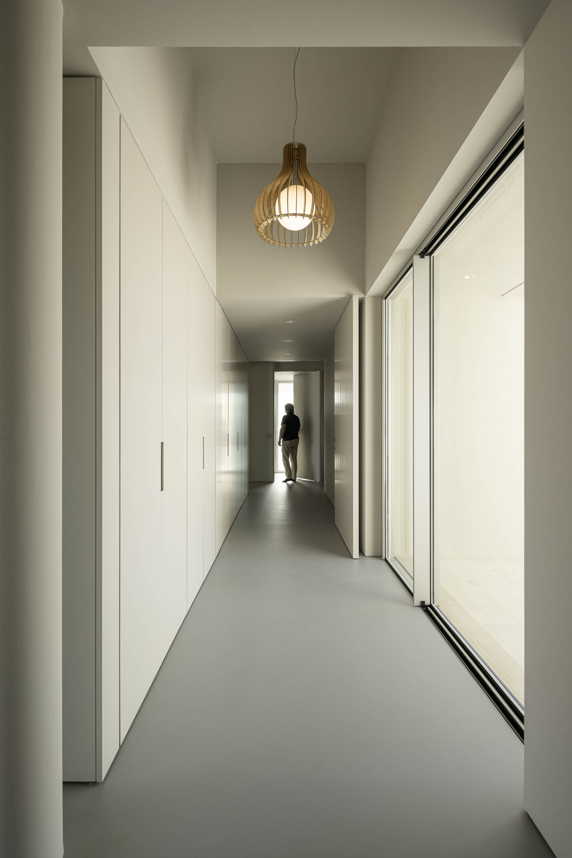 Corredor: Detalhe de um corredor com espelhos e portas brancas, pavimento cerâmico cinzento. — Casa na Romeira arquitetura dp arquitectos em Santarém