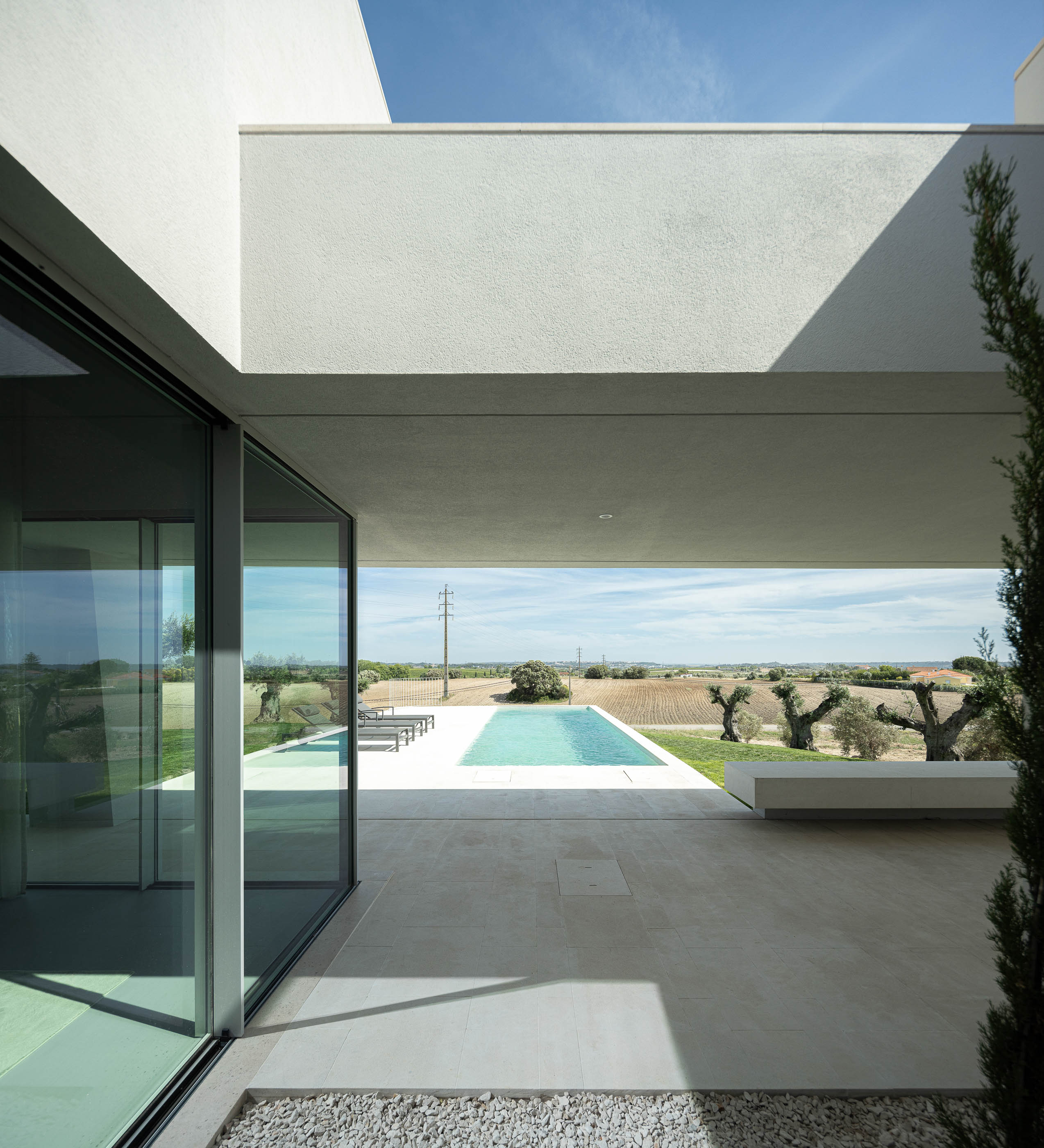 Casa de banho: Vista do quarto para a casa de banho com lavatórios de pousar, espelho e pavimento cerâmico. — Casa na Romeira arquitetura dp arquitectos em Santarém