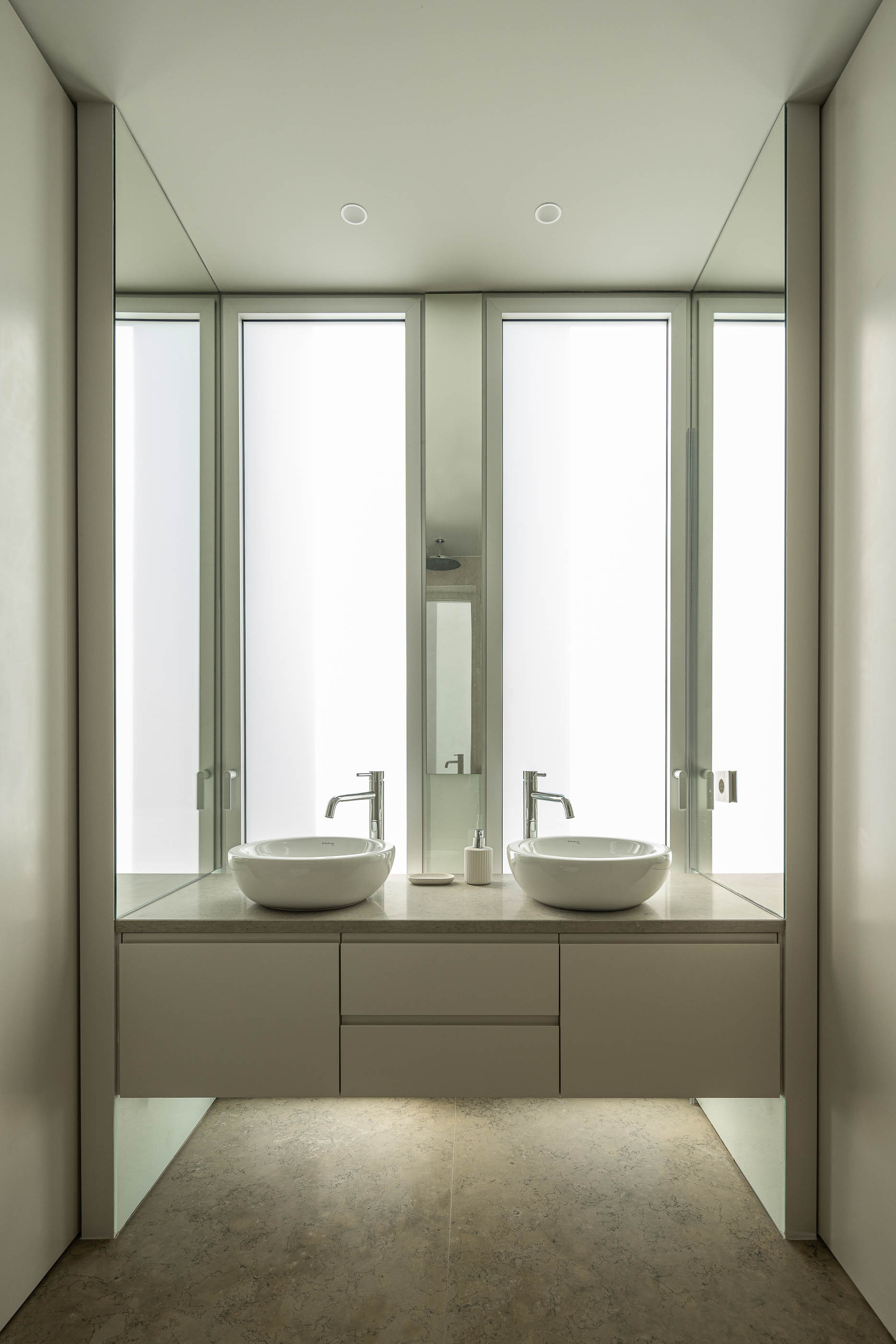 Sala de estar: Sala de estar ampla com estantes brancas iluminadas, sofá preto, lareira e pavimento cinzento. — Casa na Romeira arquitetura dp arquitectos em Santarém