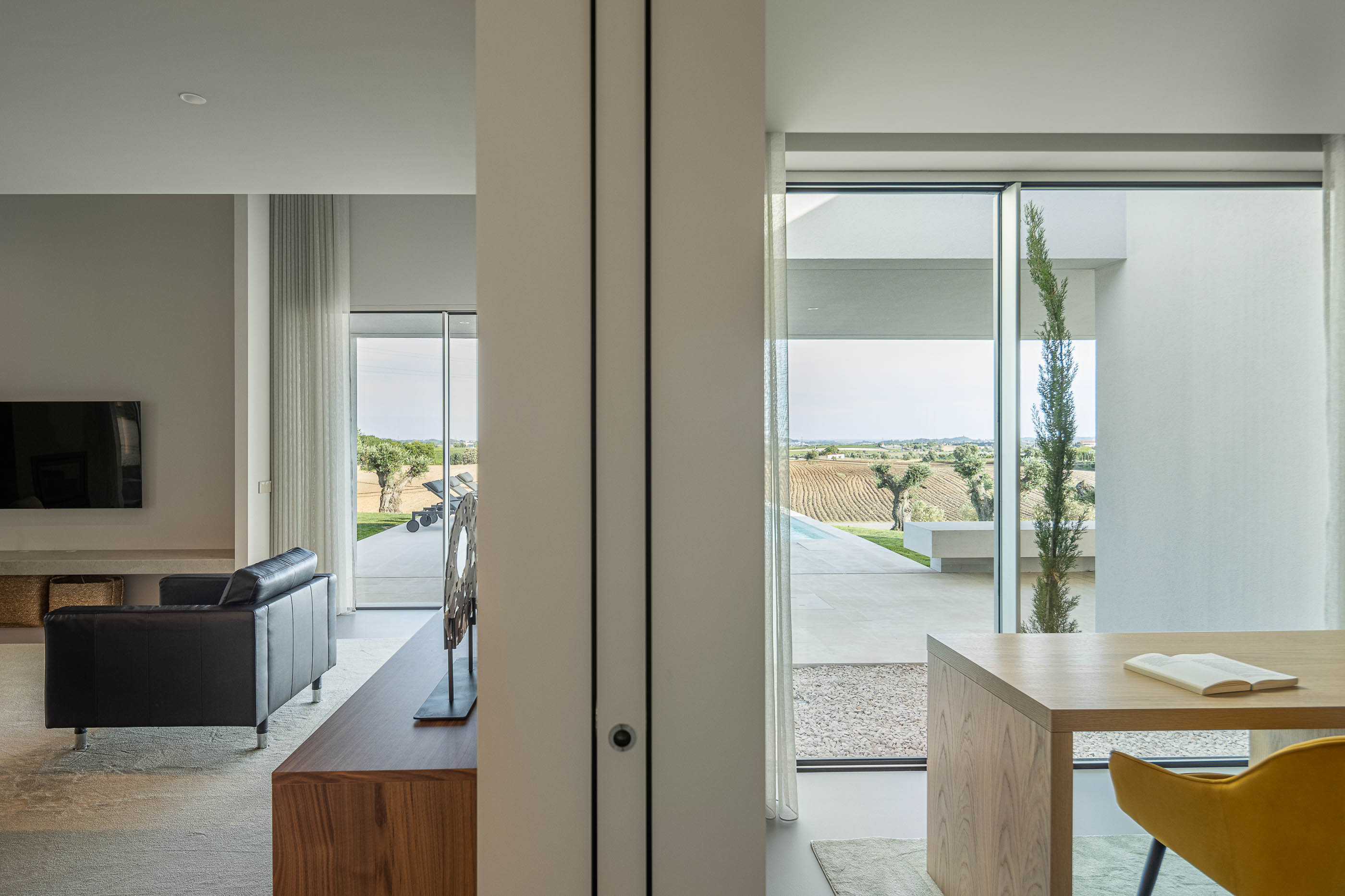 Sala de estar: Detalhe das estantes brancas iluminadas com livros e objetos decorativos. — Casa na Romeira arquitetura dp arquitectos em Santarém
