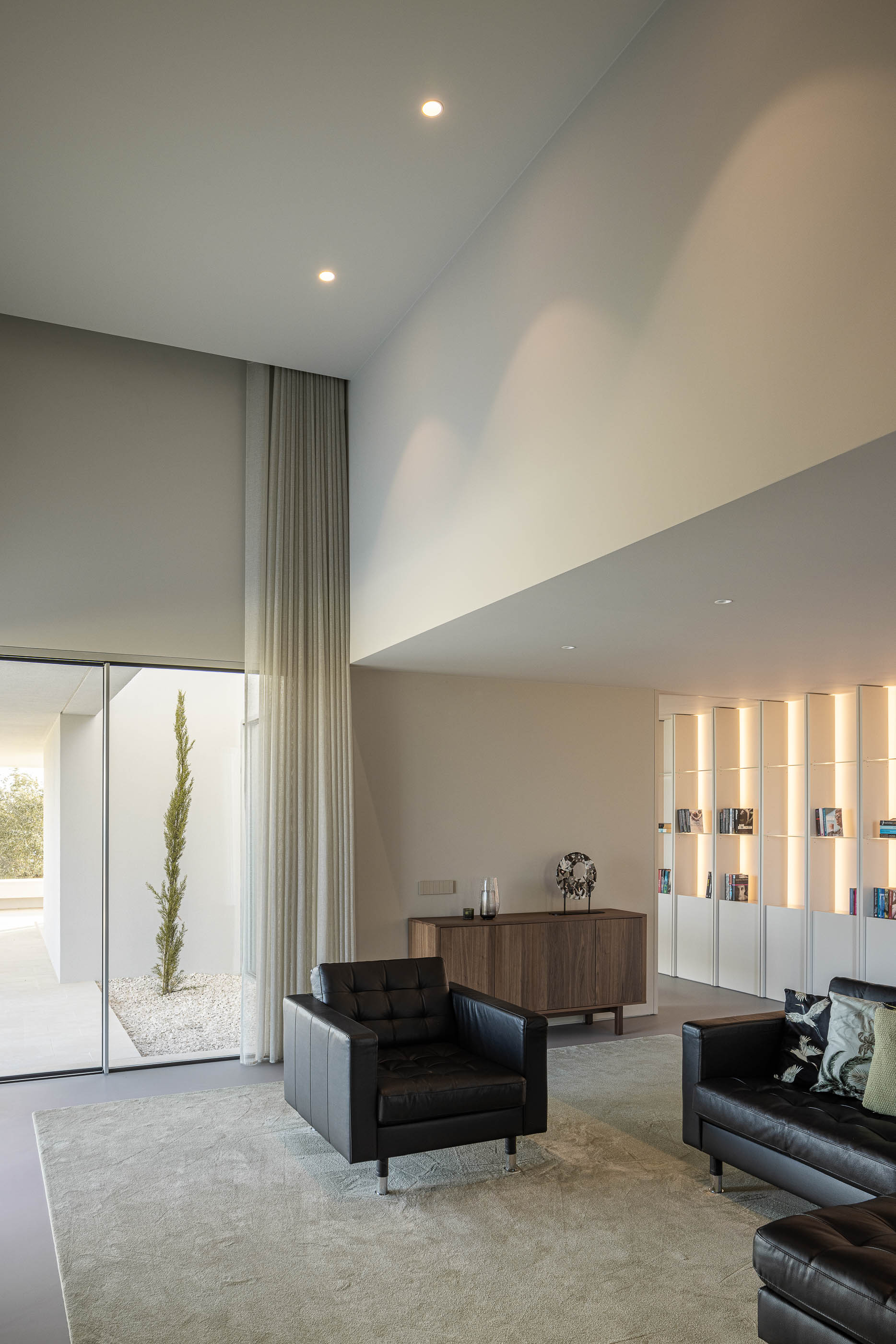 Sala de jantar: Zona de jantar com mesa de madeira rústica, cadeiras amarelas e estantes brancas iluminadas. — Casa na Romeira arquitetura dp arquitectos em Santarém