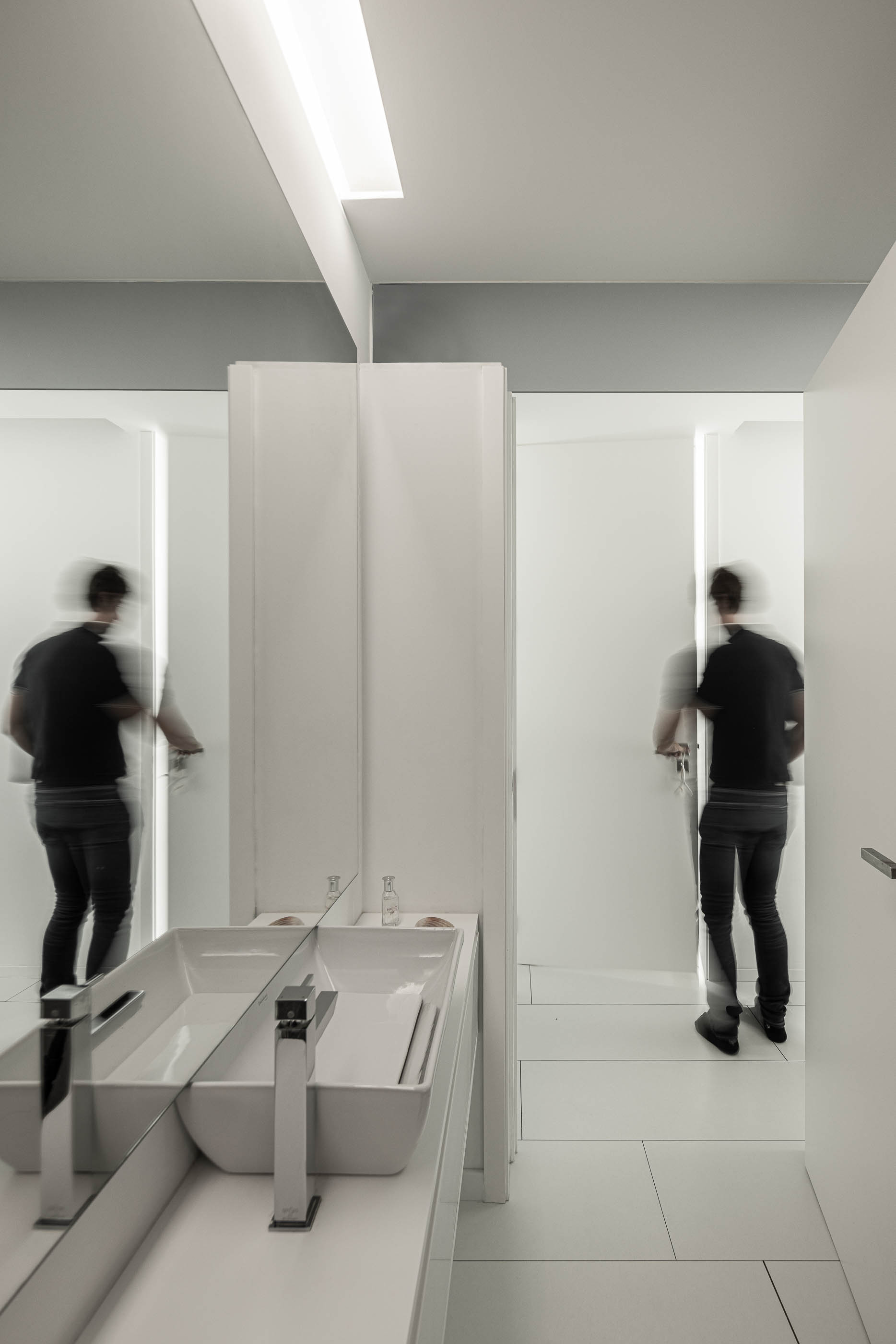 Casa de banho: Espelho duplo sobre lavatórios brancos, com portas de acesso às cabines sanitárias. — Casa Cor de Sal arquitetura Rómulo Neto Arquitectos em Ílhavo