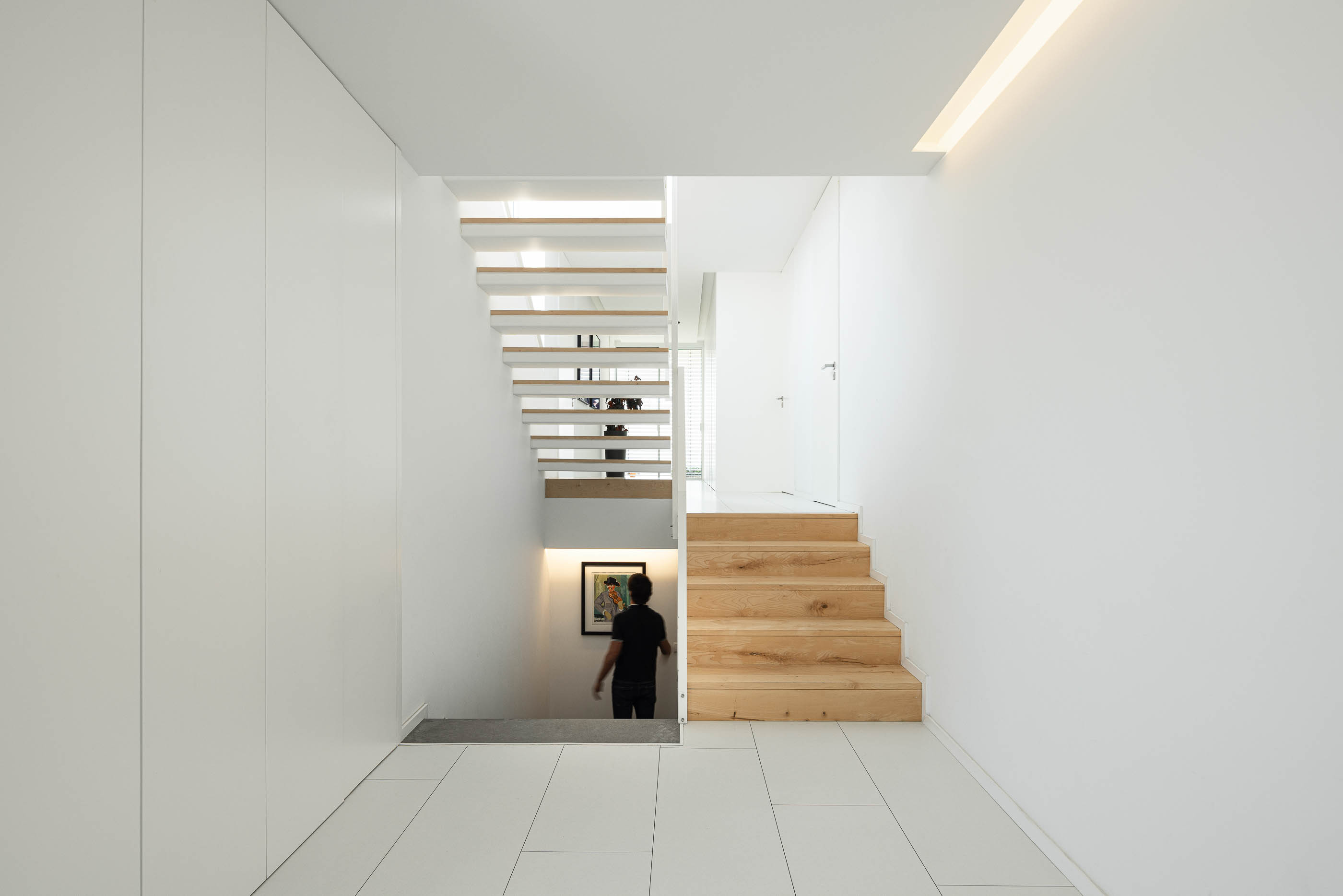 Hall: Escadaria de madeira e branca, com pavimento cerâmico e armários embutidos brancos. — Casa Cor de Sal arquitetura Rómulo Neto Arquitectos em Ílhavo