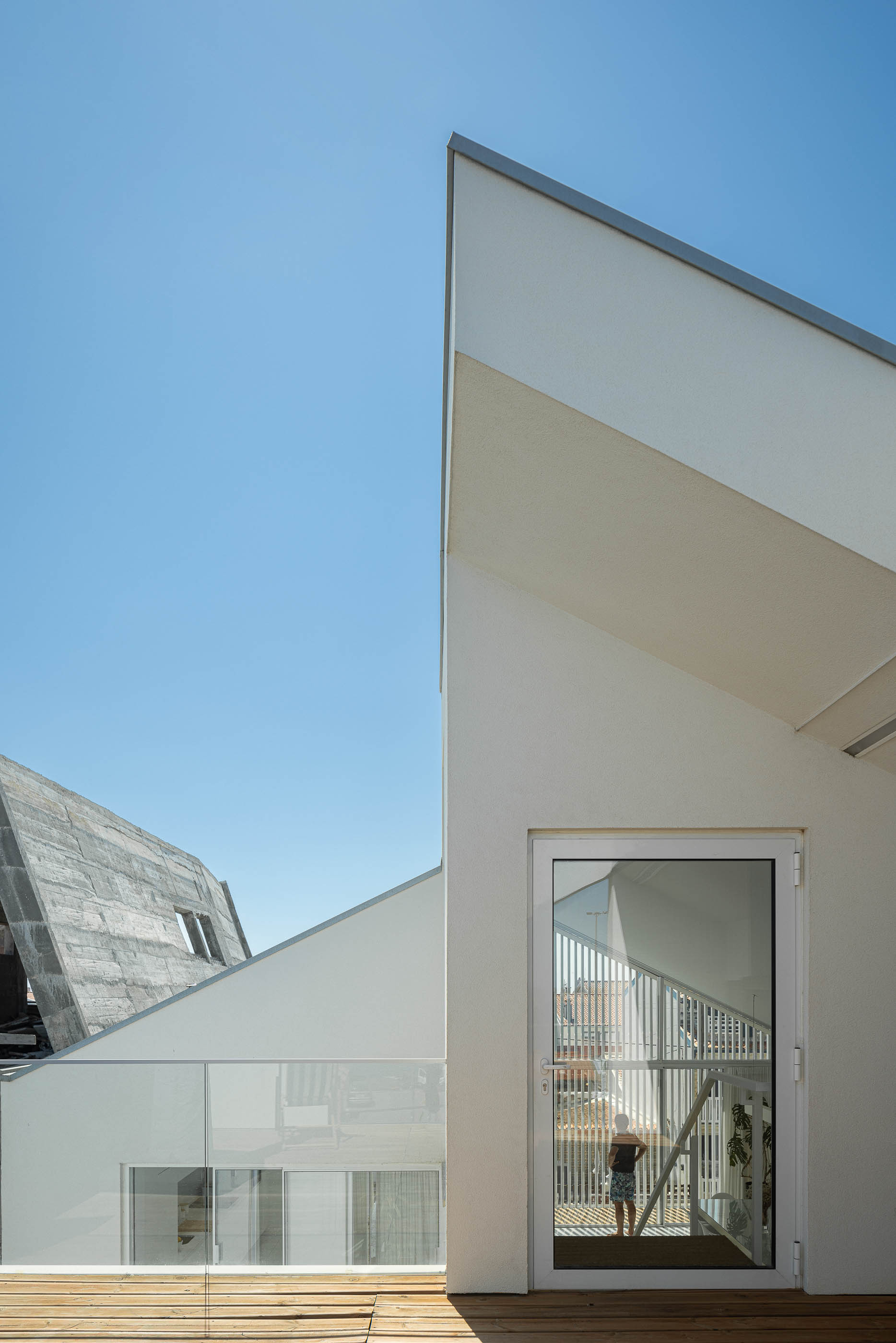 Exterior: Detalhe da arquitetura da casa, com varanda e escadaria visíveis através da janela. — Casa Cor de Sal arquitetura Rómulo Neto Arquitectos em Ílhavo