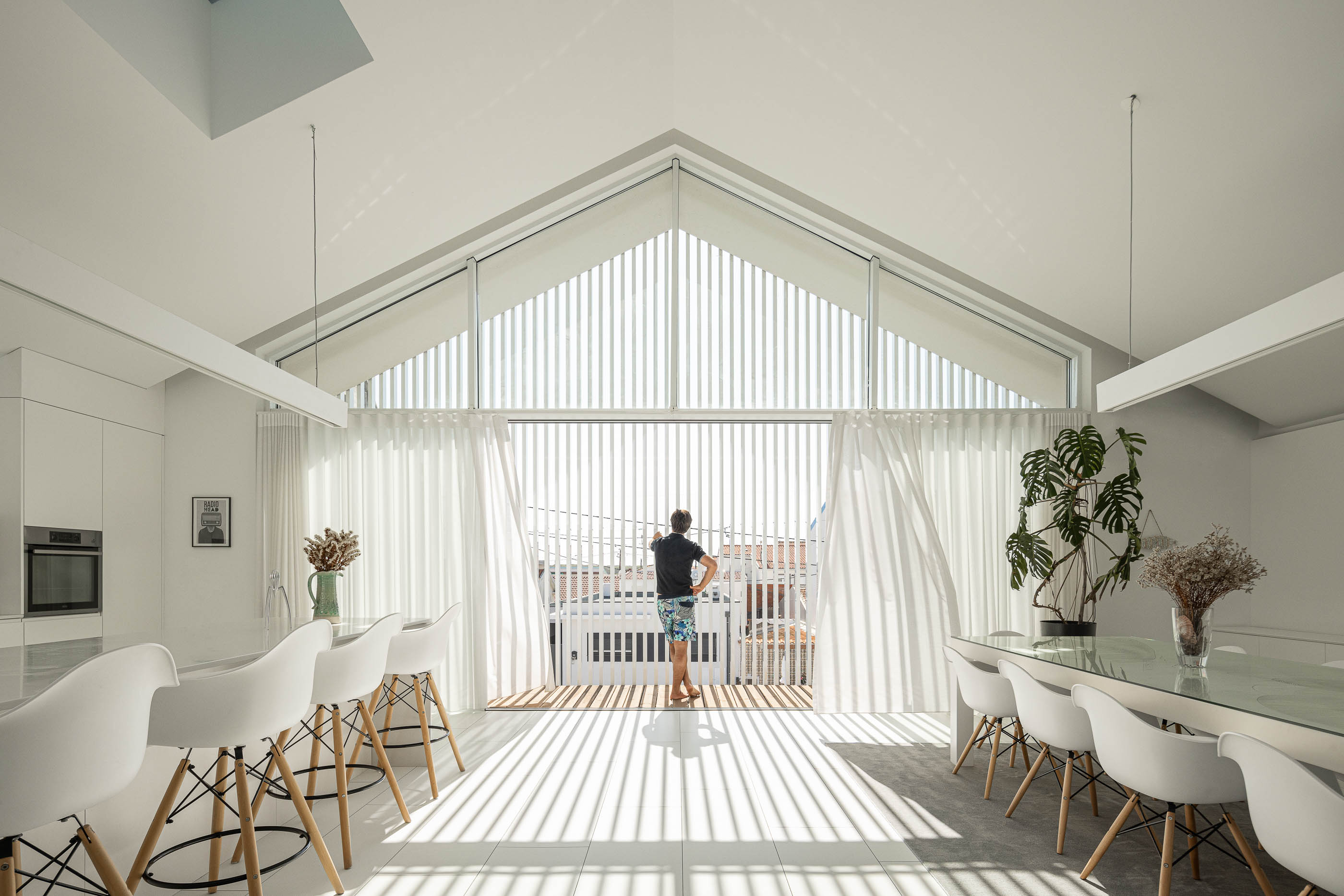 Cozinha: Vista geral da cozinha com ilha central, mesa de jantar e claraboia no teto. — Casa Cor de Sal arquitetura Rómulo Neto Arquitectos em Ílhavo