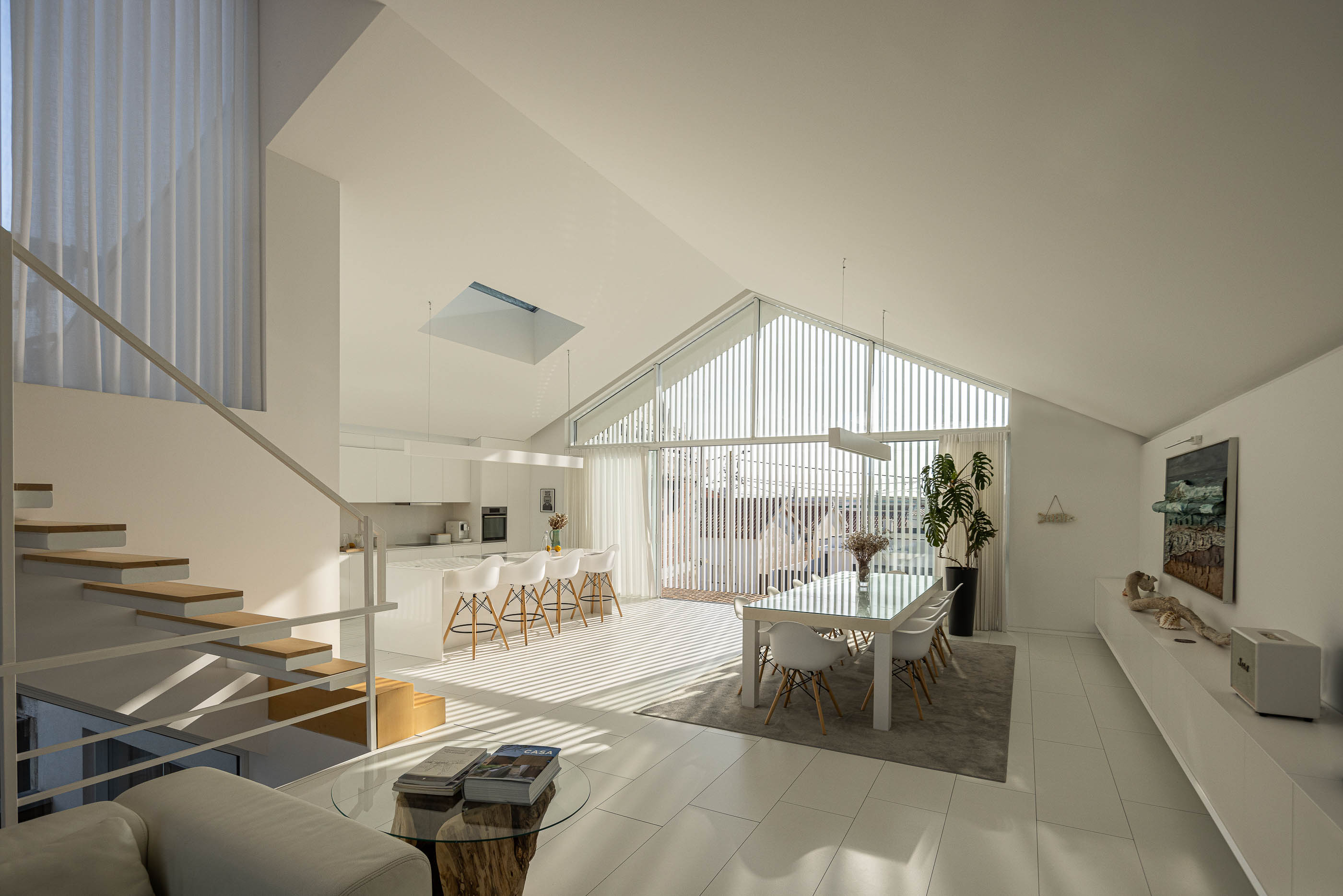 Cozinha: Espaço amplo com cozinha, sala de jantar e escadaria, com muita luz natural. — Casa Cor de Sal arquitetura Rómulo Neto Arquitectos em Ílhavo
