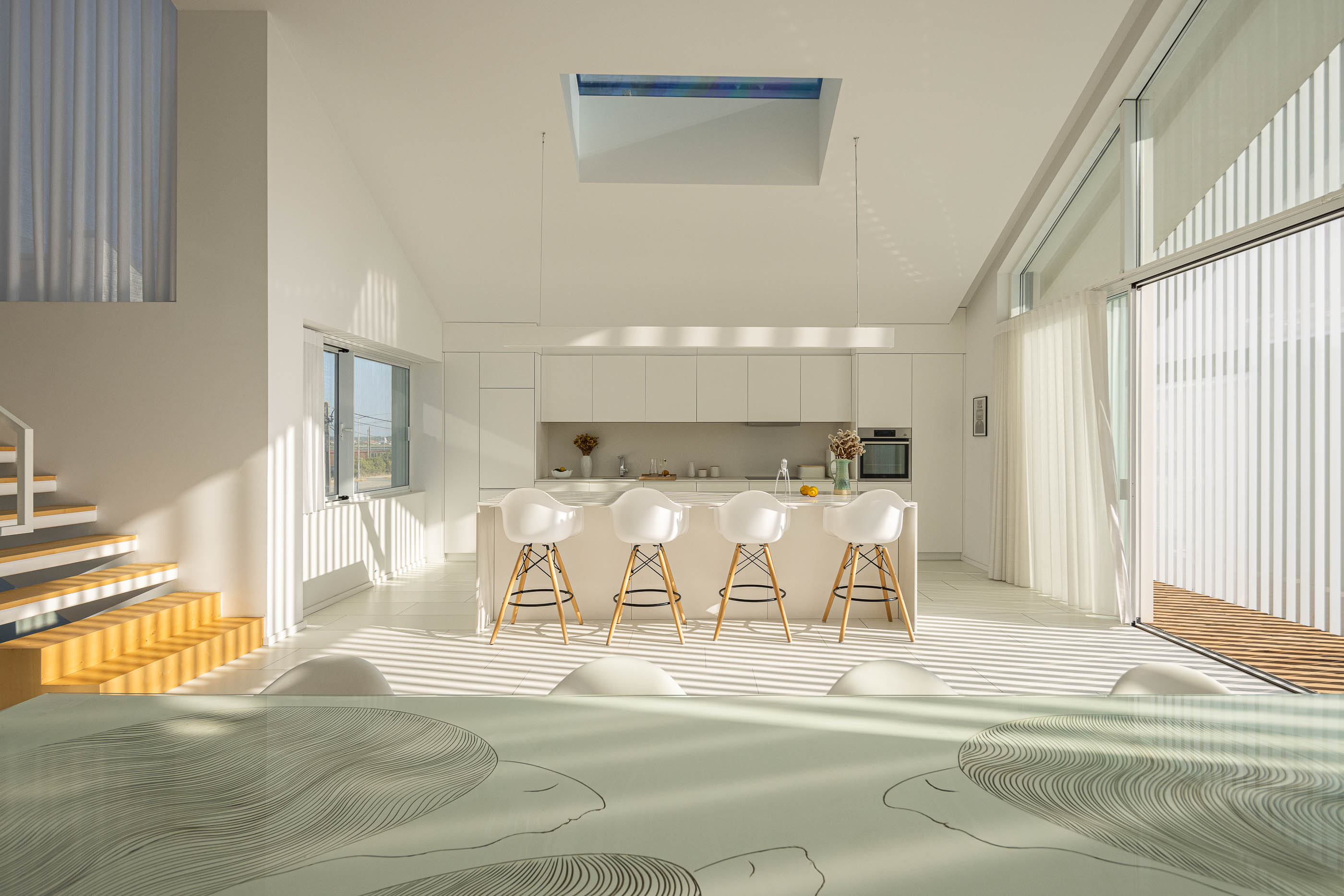 Cozinha: Ilha central com bancos brancos, armários brancos e claraboia no teto. — Casa Cor de Sal arquitetura Rómulo Neto Arquitectos em Ílhavo