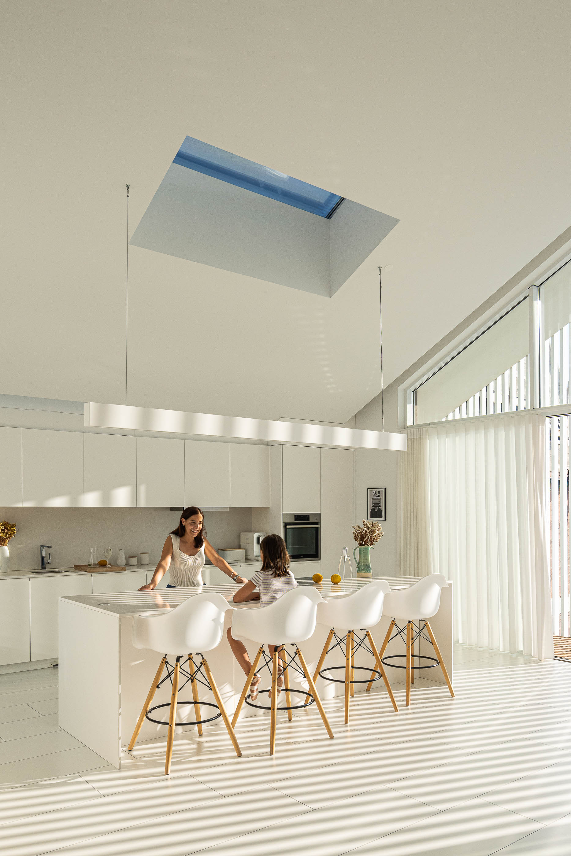 Sala de jantar: Detalhe do candeeiro suspenso e da cortina branca na janela. — Casa Cor de Sal arquitetura Rómulo Neto Arquitectos em Ílhavo