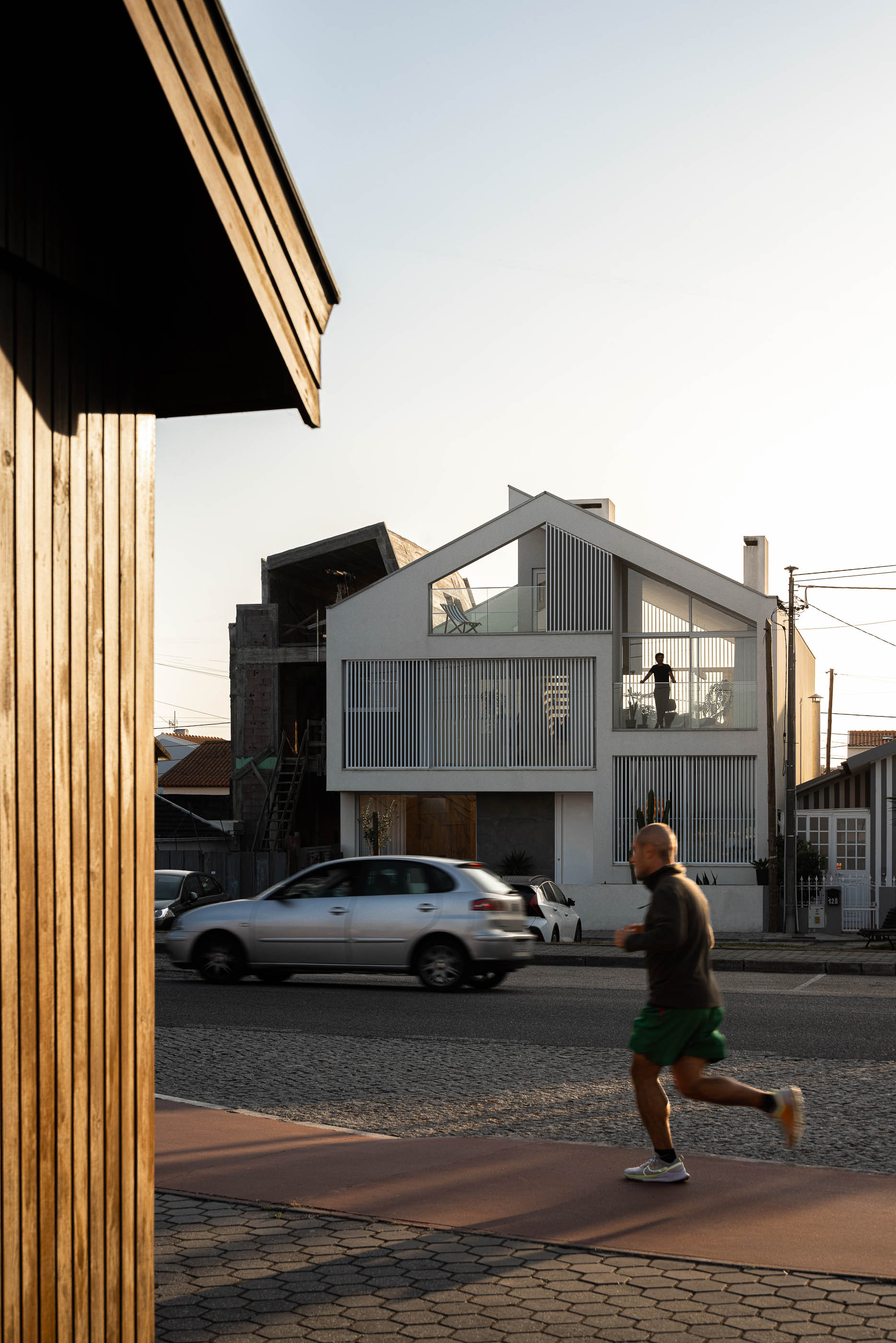 Exterior: Fachada da casa iluminada à noite, com brises verticais e varandas. — Casa Cor de Sal arquitetura Rómulo Neto Arquitectos em Ílhavo