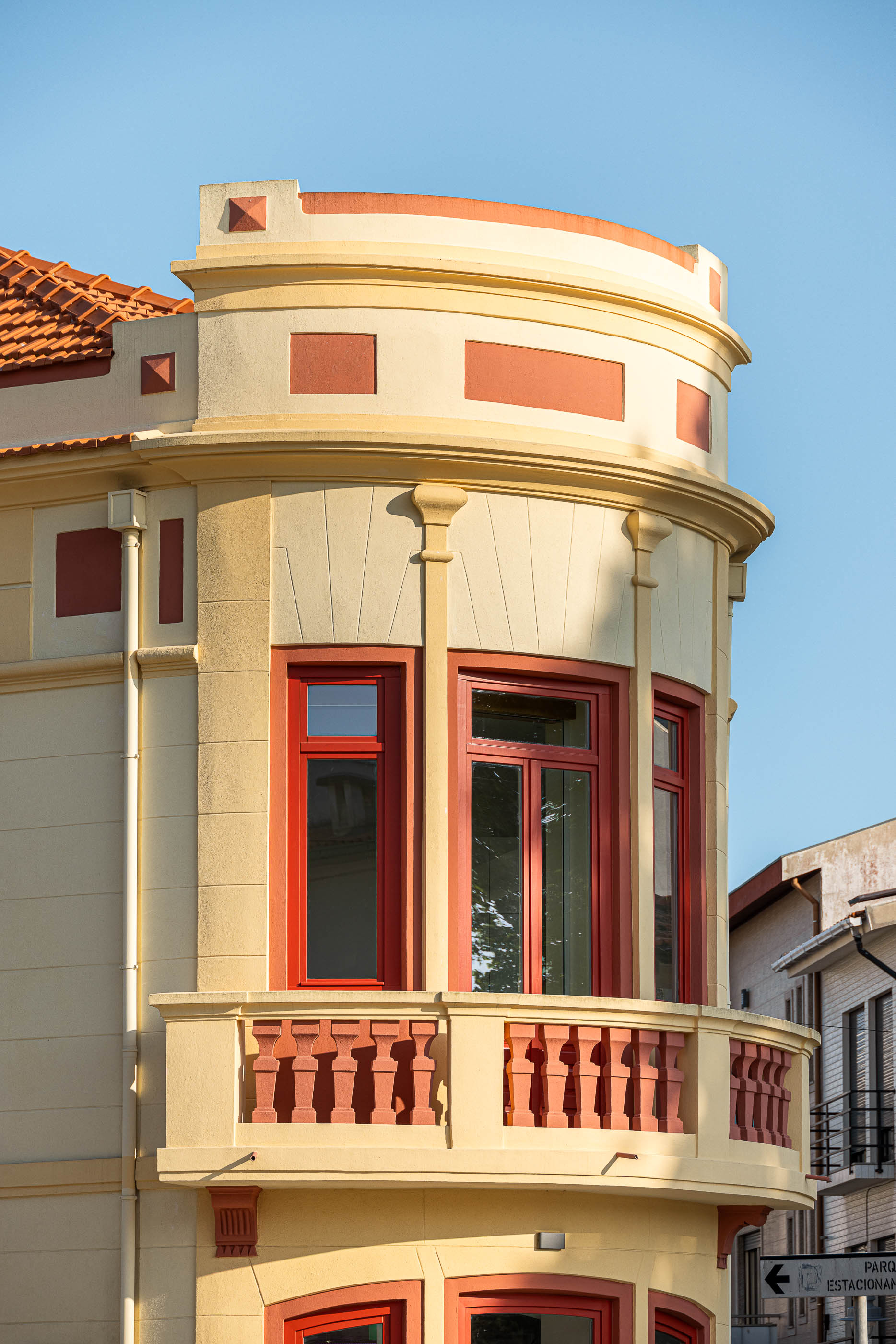 Fachada: Detalhe da varanda curva do edifício, com balaustrada e caixilharia vermelha. — A'mar arquitetura REM'A Arquitectos em Póvoa de Varzim