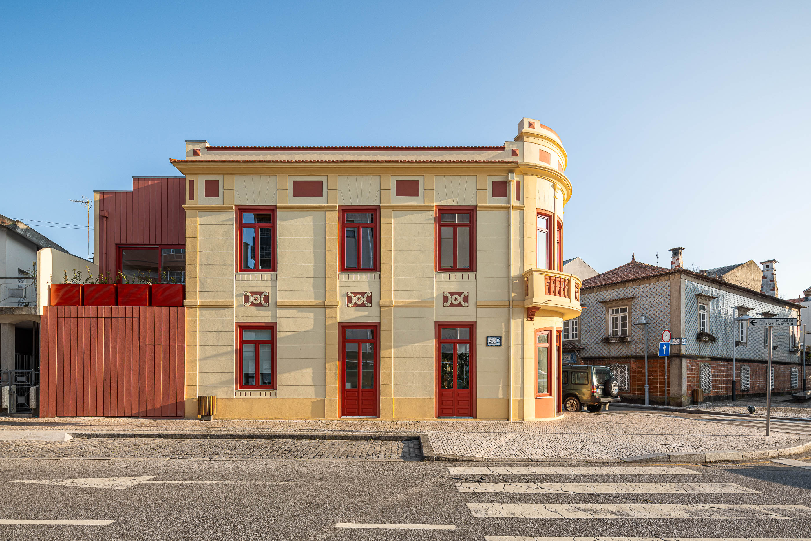 Fachada: Edifício com anexo moderno em madeira, mantendo a fachada clássica em tons creme e vermelho. — A'mar arquitetura REM'A Arquitectos em Póvoa de Varzim