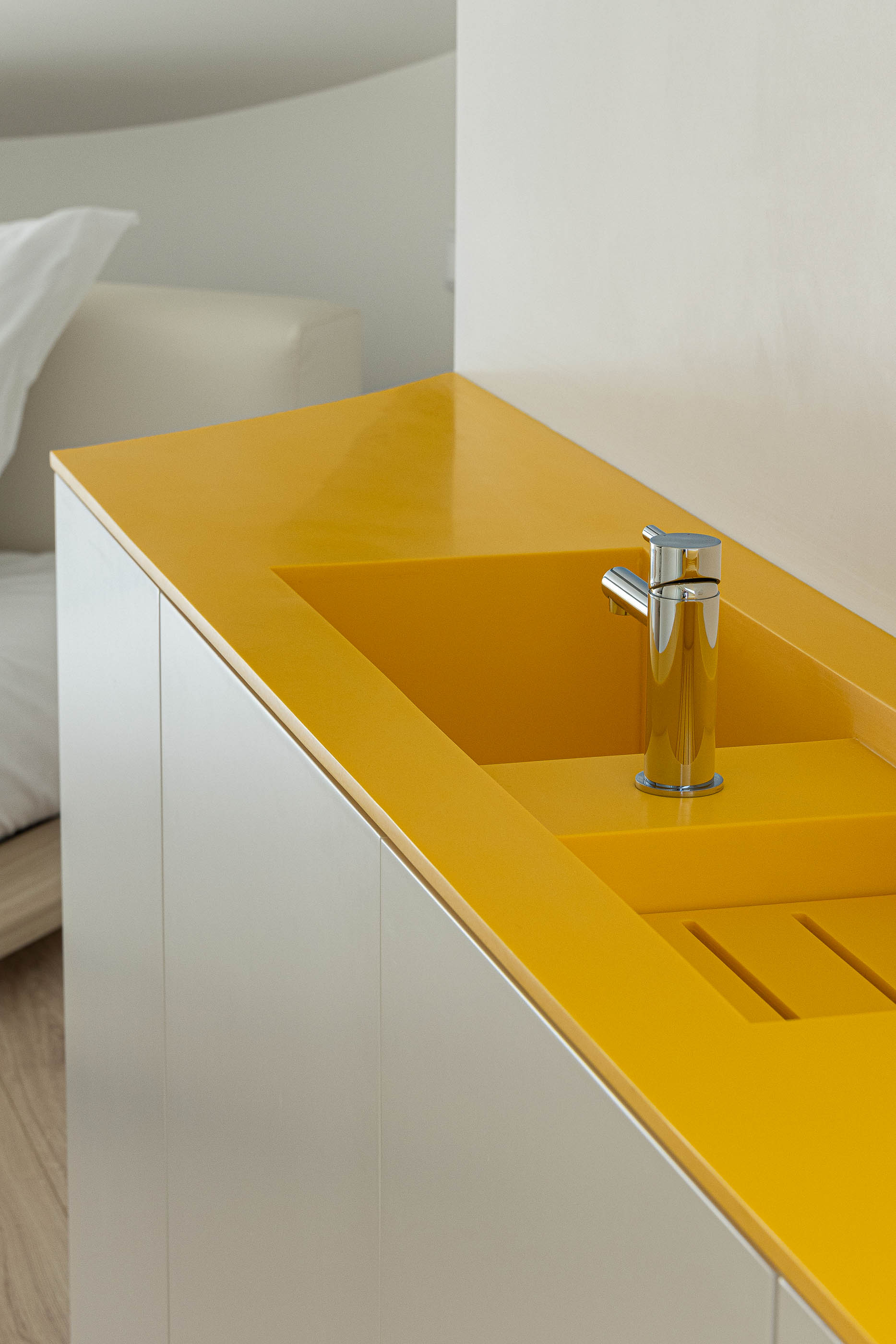 Quarto: Detalhe da kitchenette com lavatório amarelo embutido num armário branco. — A'mar arquitetura REM'A Arquitectos em Póvoa de Varzim