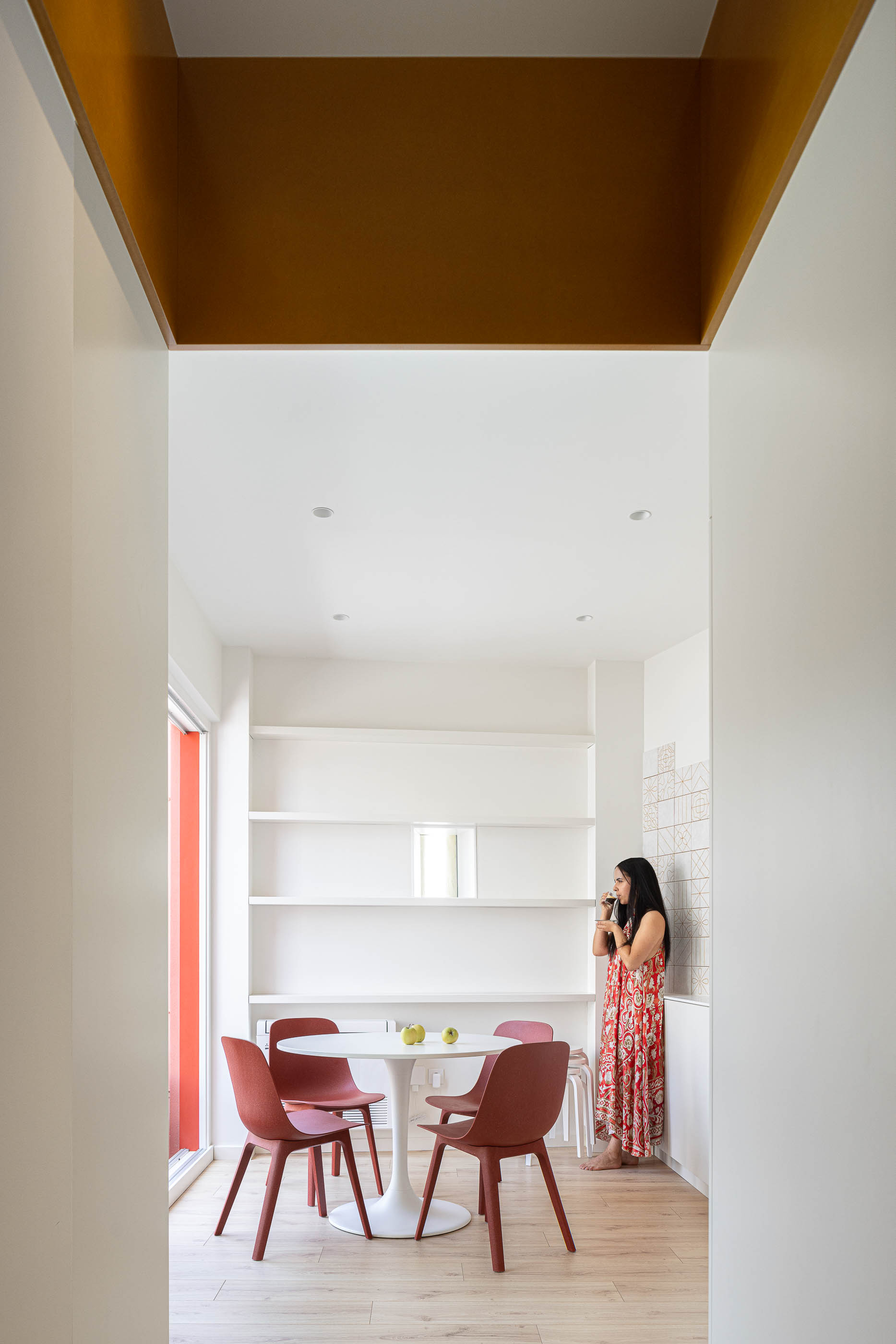 Cozinha: Interior com mesa redonda, cadeiras vermelhas, armários brancos e prateleiras na parede. — A'mar arquitetura REM'A Arquitectos em Póvoa de Varzim