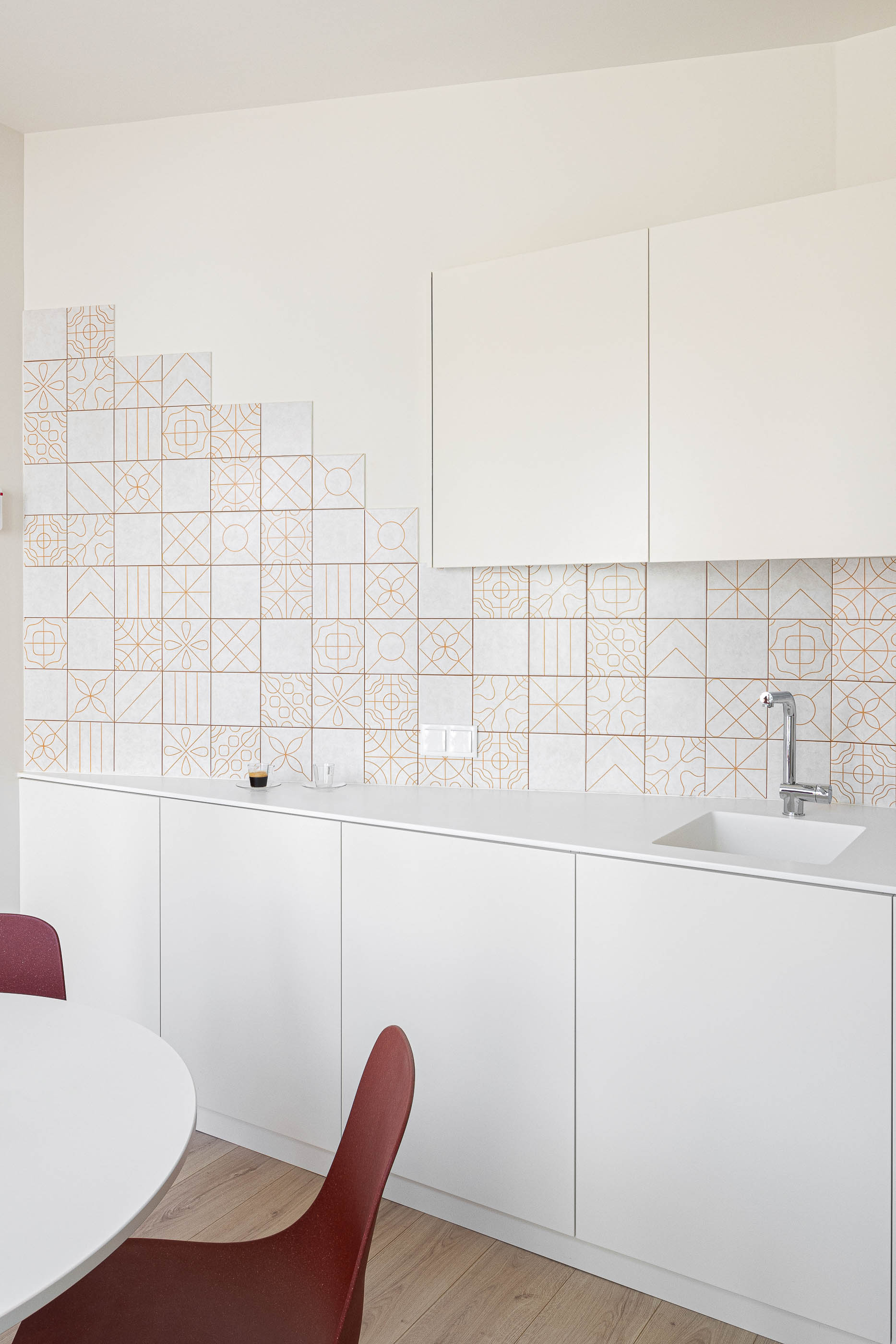 Cozinha: Interior com armários brancos, revestimento cerâmico decorado e mesa redonda com cadeiras. — A'mar arquitetura REM'A Arquitectos em Póvoa de Varzim
