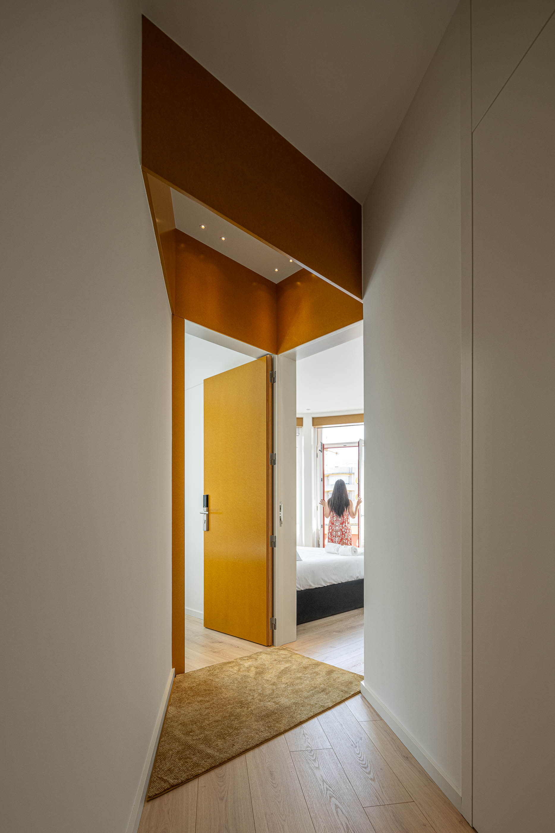 Corredor: Corredor com alcatifa, porta amarela e vista para o quarto com cama de casal. — A'mar arquitetura REM'A Arquitectos em Póvoa de Varzim