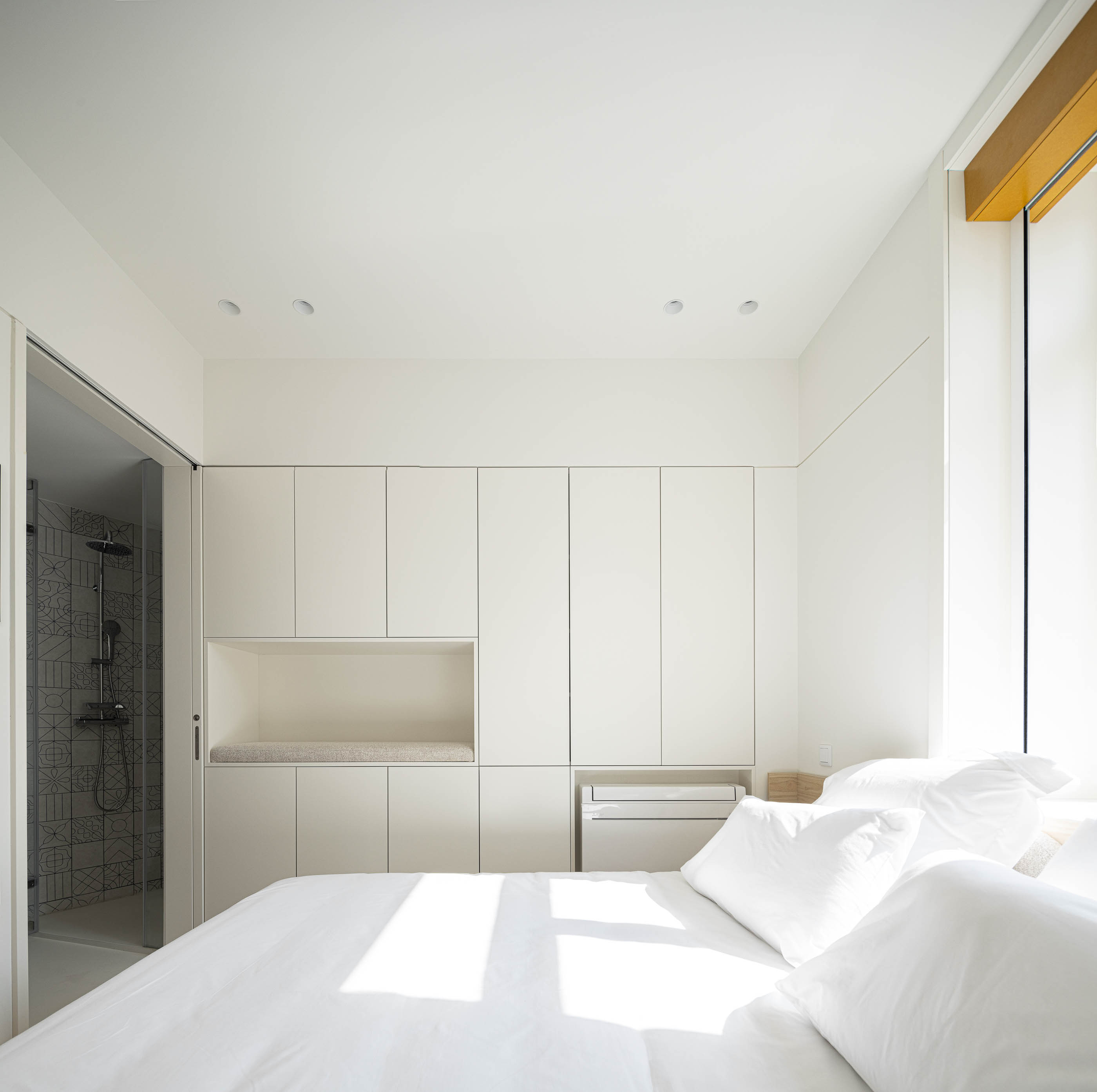 Quarto: Quarto com cama de casal, armários brancos e duche com revestimento cerâmico decorado. — A'mar arquitetura REM'A Arquitectos em Póvoa de Varzim