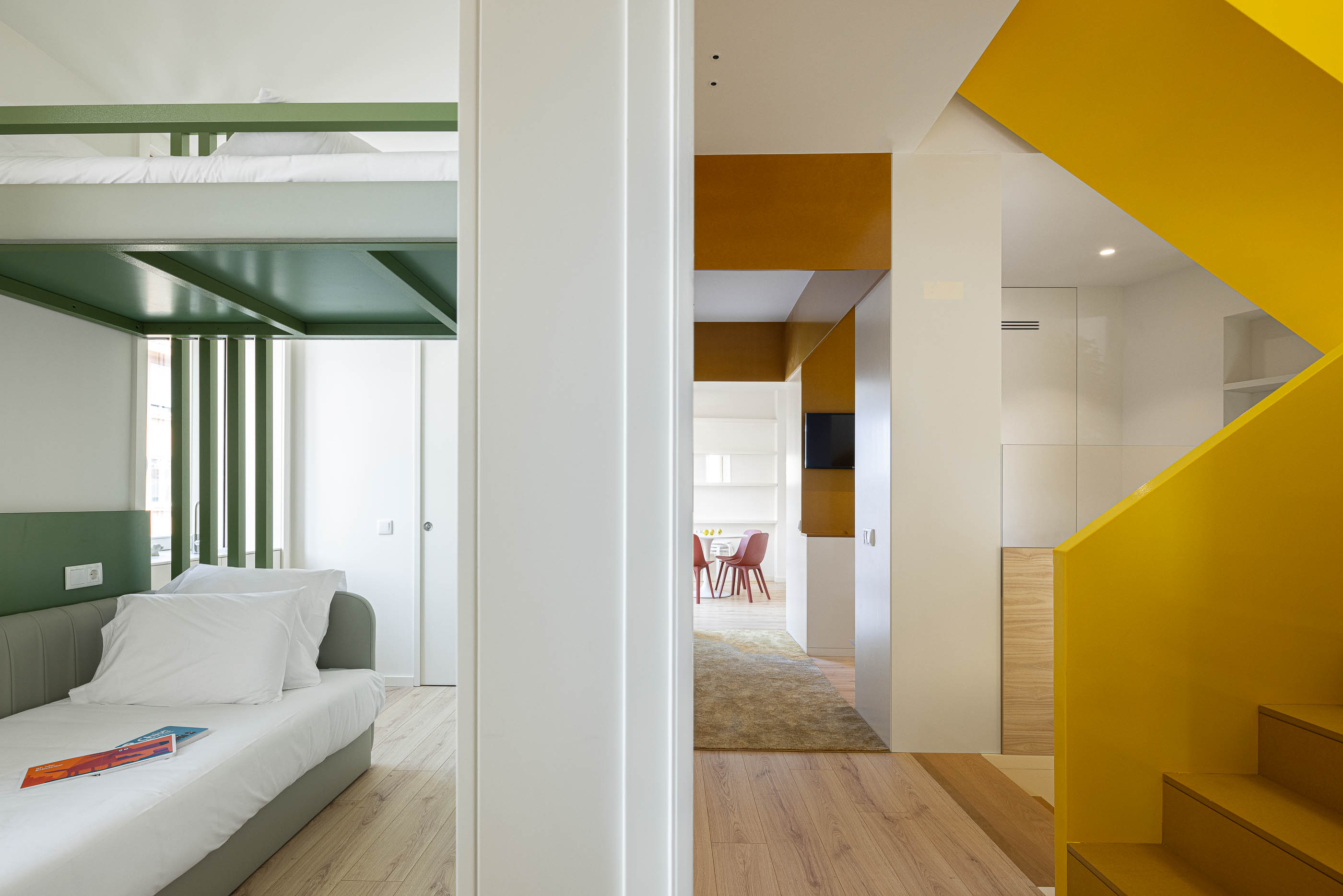 Interior: Vista do quarto com beliche verde para a escada amarela e cozinha. — A'mar arquitetura REM'A Arquitectos em Póvoa de Varzim