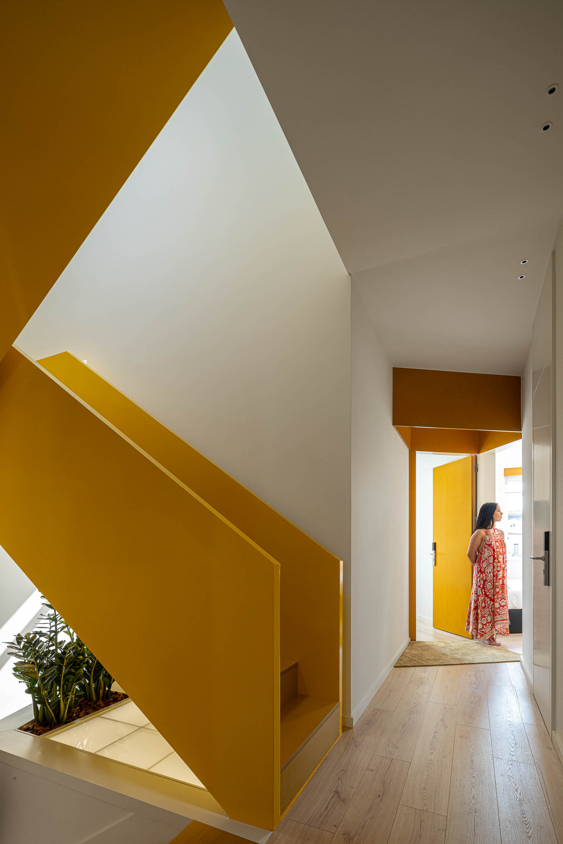Corredor: Vista da escada amarela para o corredor e quarto com porta amarela. — A'mar arquitetura REM'A Arquitectos em Póvoa de Varzim