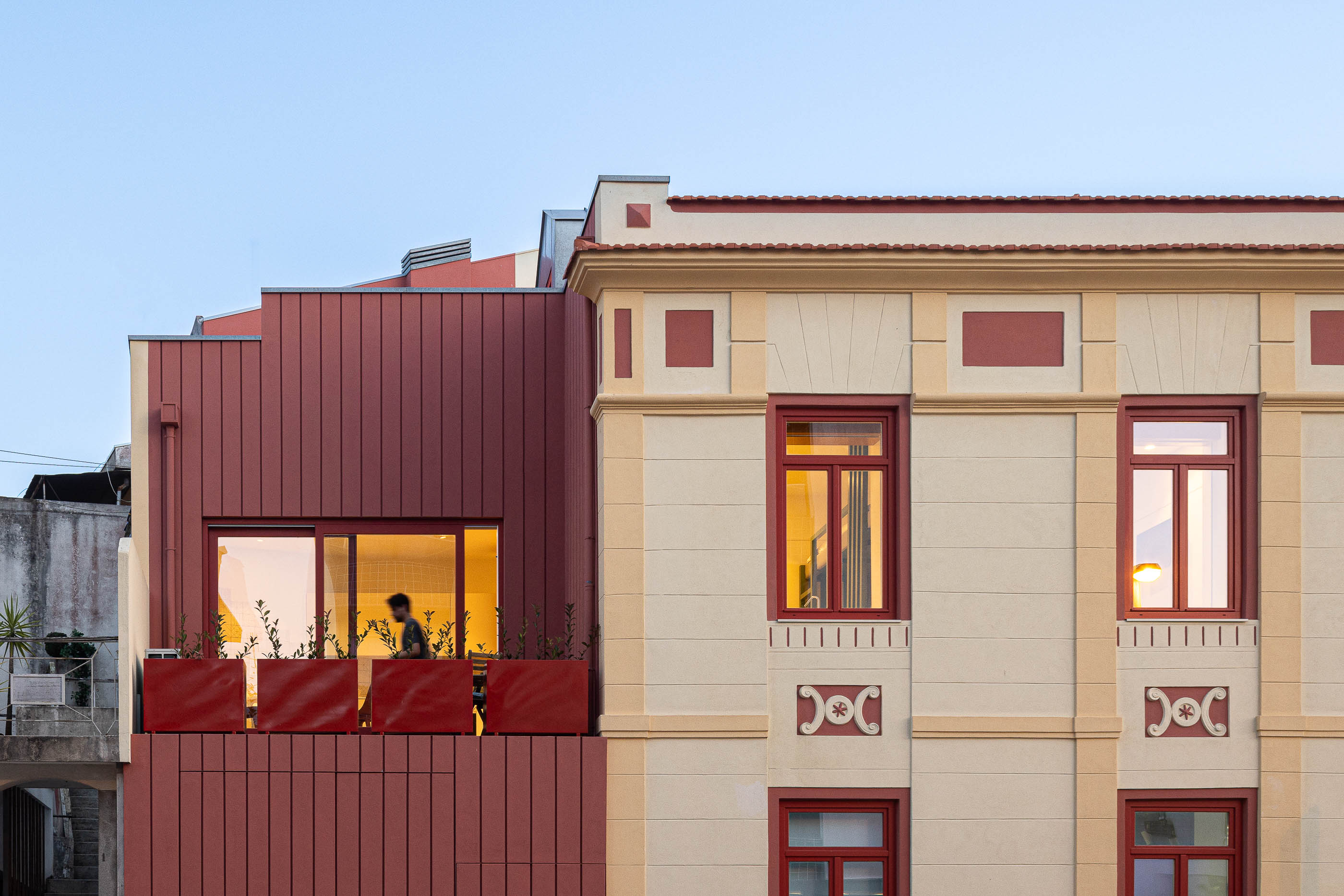 Fachada: Vista da fachada clássica com anexo moderno em madeira vermelha ao entardecer. — A'mar arquitetura REM'A Arquitectos em Póvoa de Varzim