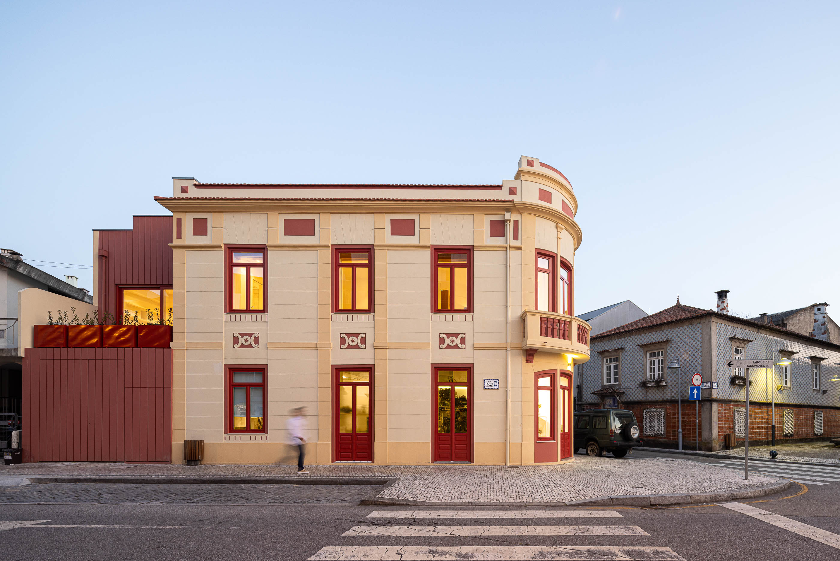 Fachada: Vista geral do edifício com fachada clássica e anexo moderno em madeira vermelha ao entardecer. — A'mar arquitetura REM'A Arquitectos em Póvoa de Varzim