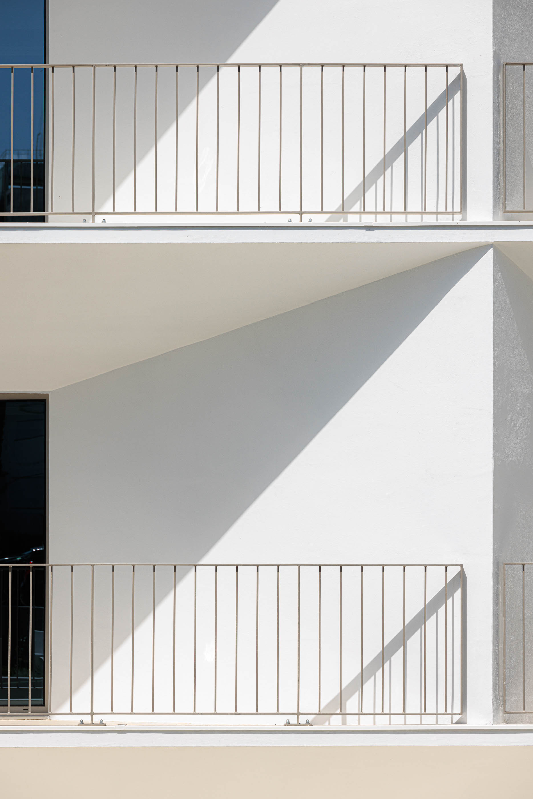 Detalhe: Varandas brancas com guardas metálicas verticais, jogo de luz e sombra. — Varandas de Salgueiros arquitetura Floret Arquitectura em Porto