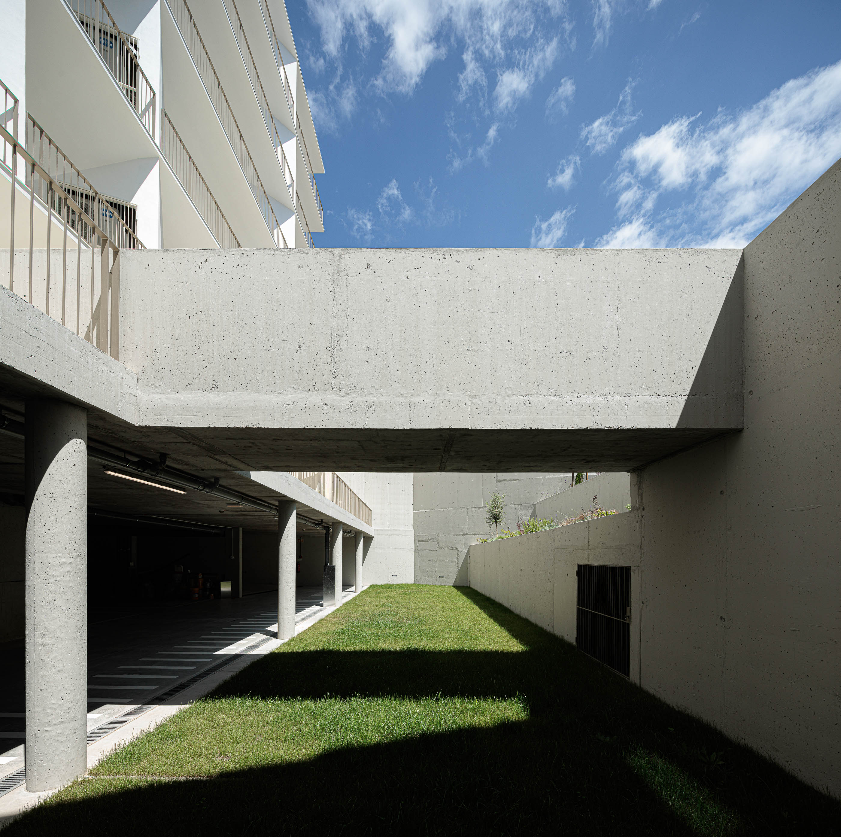 Exterior: Passagem pedonal elevada em betão, relvado e acesso à garagem. — Varandas de Salgueiros arquitetura Floret Arquitectura em Porto