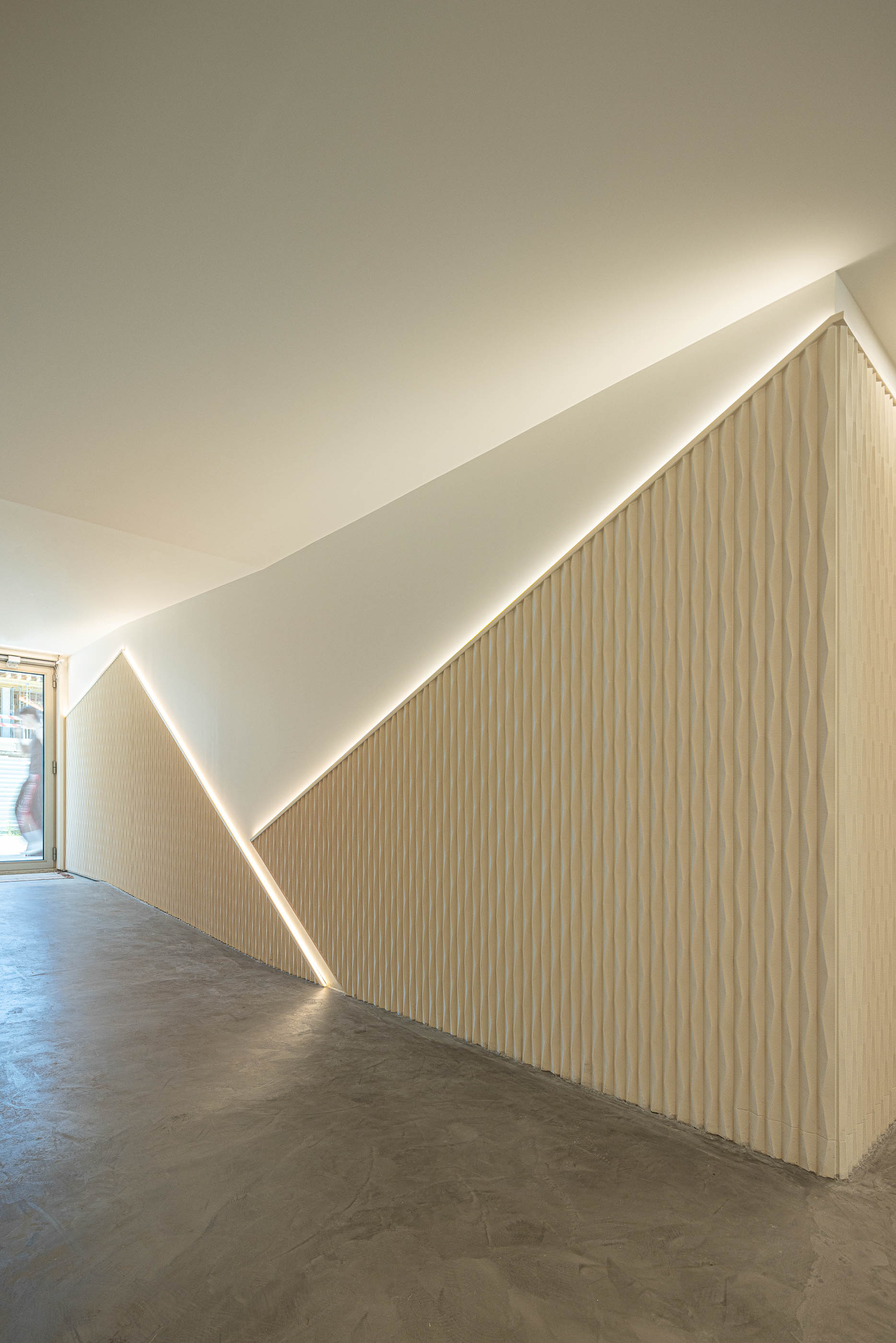 Corredor: Detalhe da parede texturada com iluminação indireta e pavimento cinzento. — Varandas de Salgueiros arquitetura Floret Arquitectura em Porto