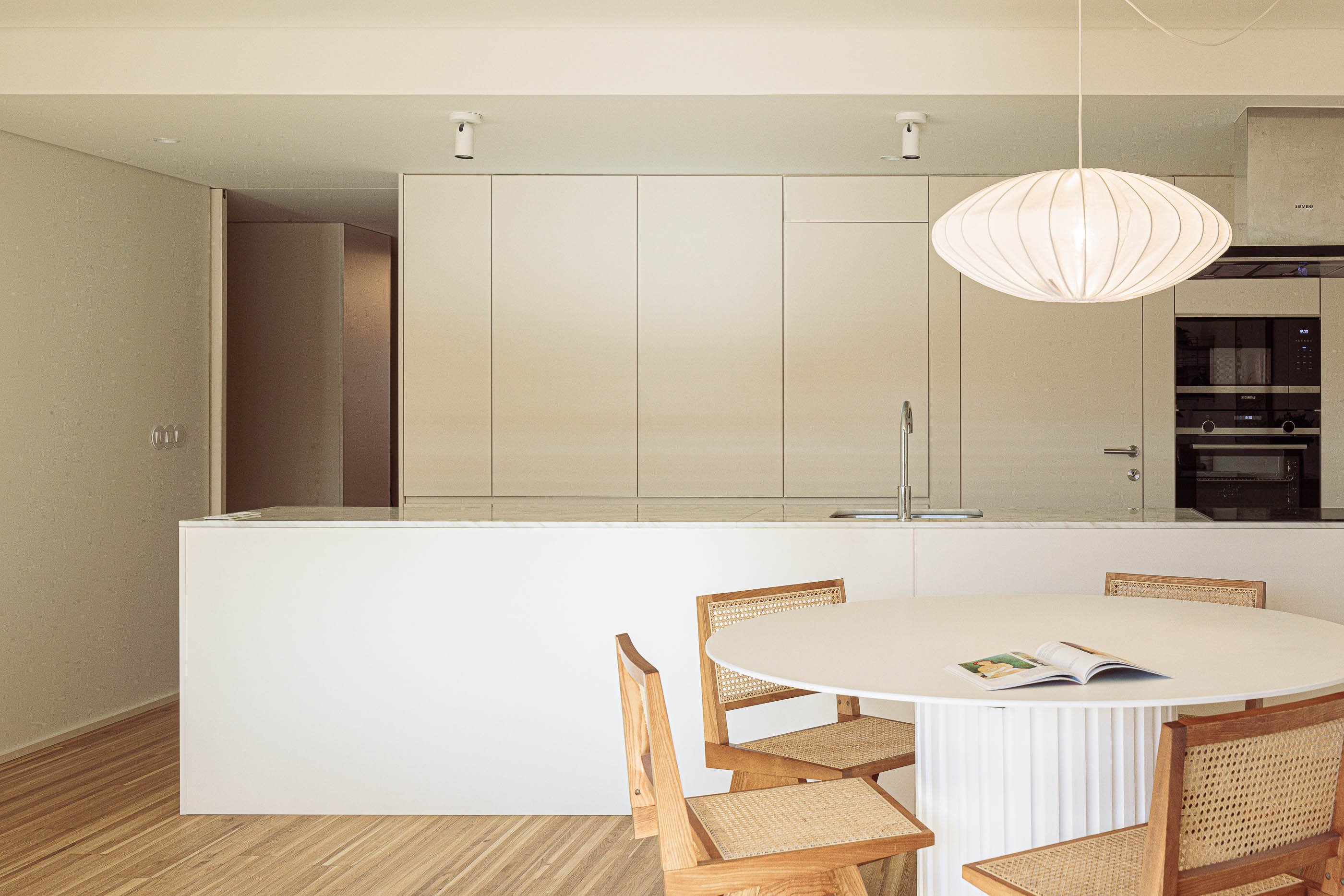 Cozinha: Cozinha minimalista branca com mesa de jantar redonda e candeeiro suspenso. — Varandas de Salgueiros arquitetura Floret Arquitectura em Porto