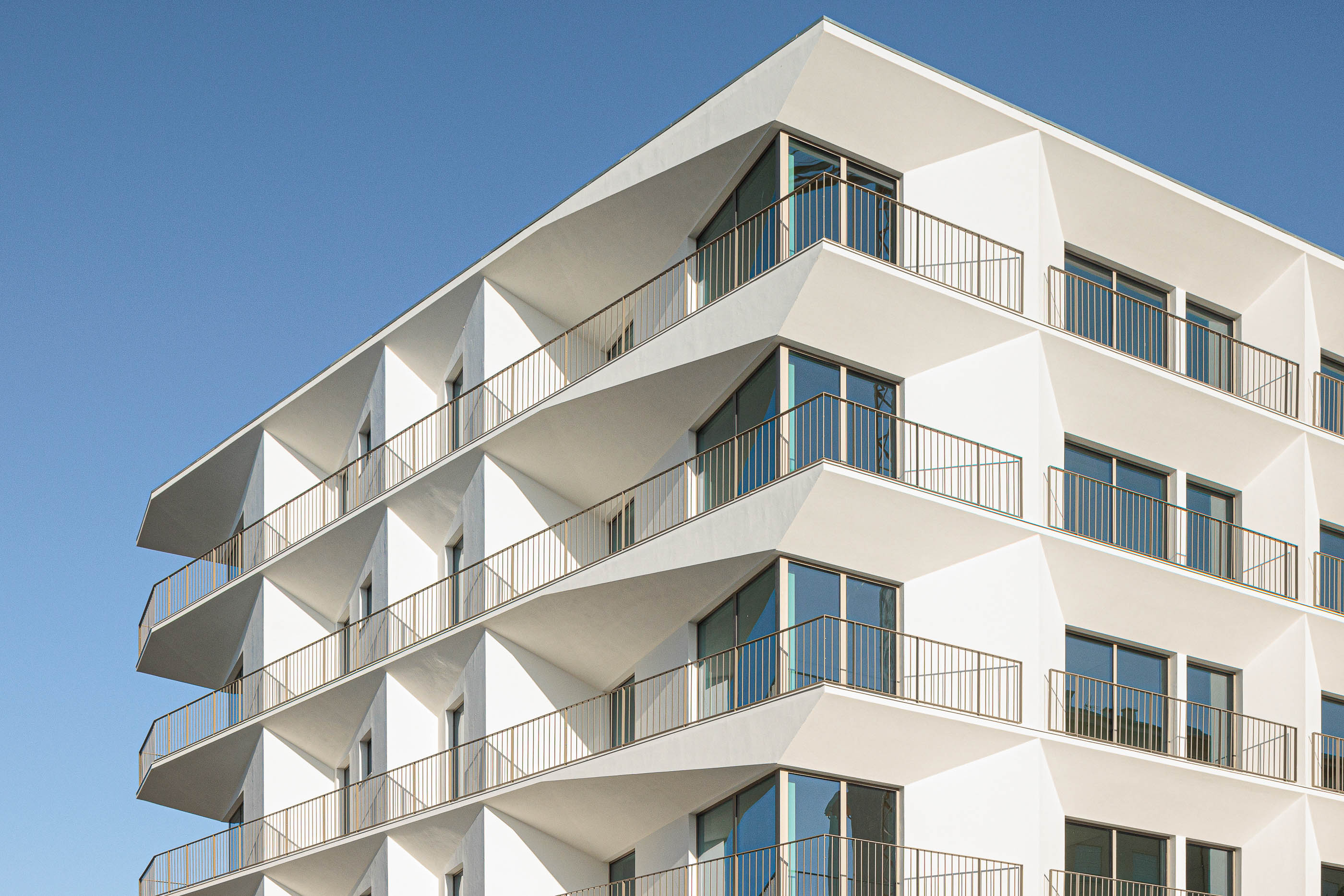 Fachada: Vista angular do edifício branco com varandas triangulares. — Varandas de Salgueiros arquitetura Floret Arquitectura em Porto