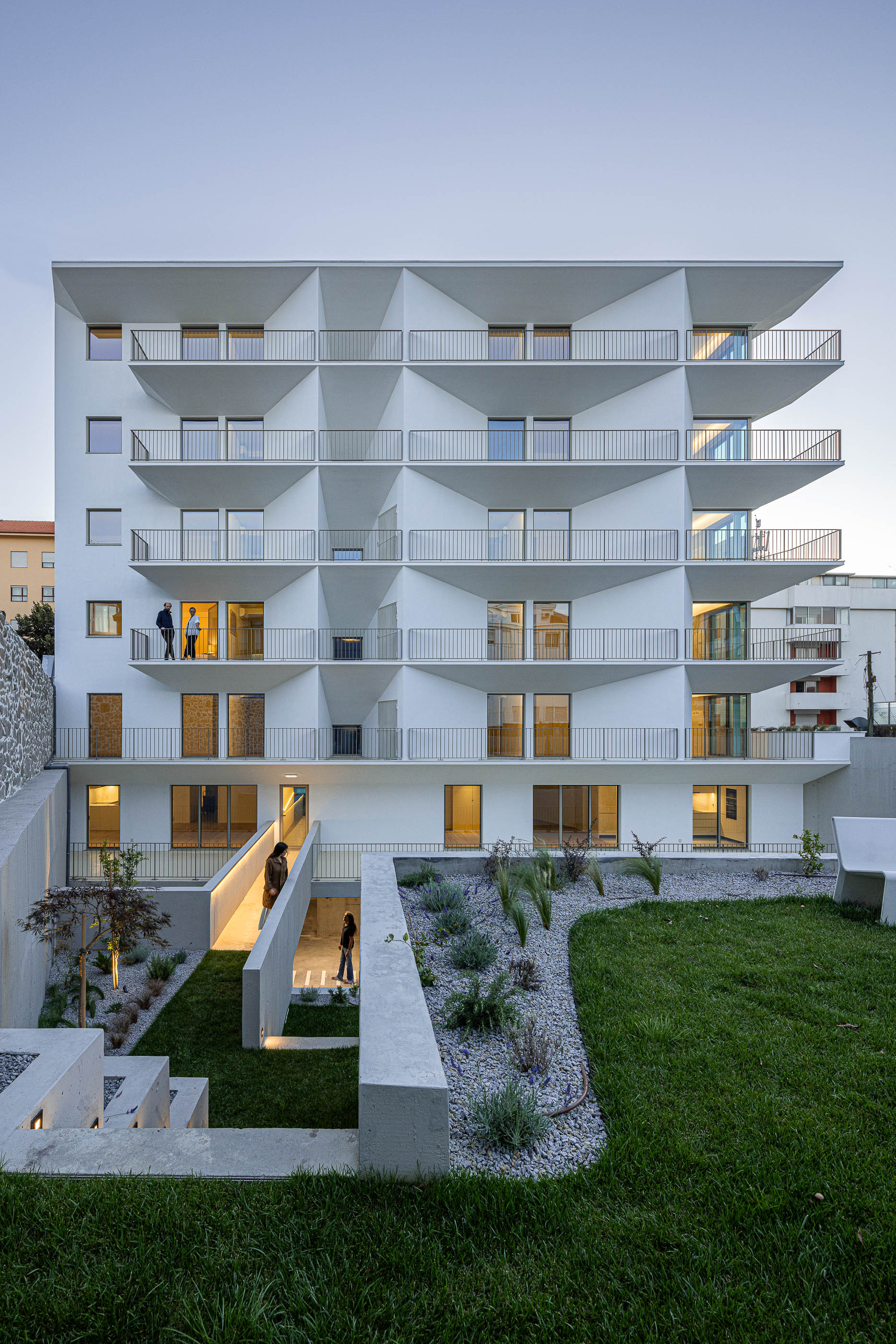 Exterior: Edifício branco com varandas triangulares, jardim e acesso pedonal elevado. — Varandas de Salgueiros arquitetura Floret Arquitectura em Porto