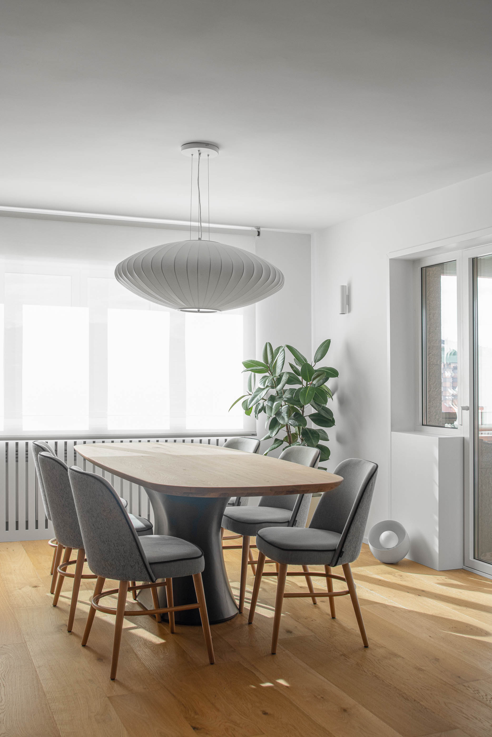 Sala de jantar com mesa oval de madeira clara, cadeiras cinzentas e candeeiro suspenso moderno. Pavimento em madeira clara. — Reforma apartamento CP em Avilés arquitetura David Olmos Arquitectos em Avilés