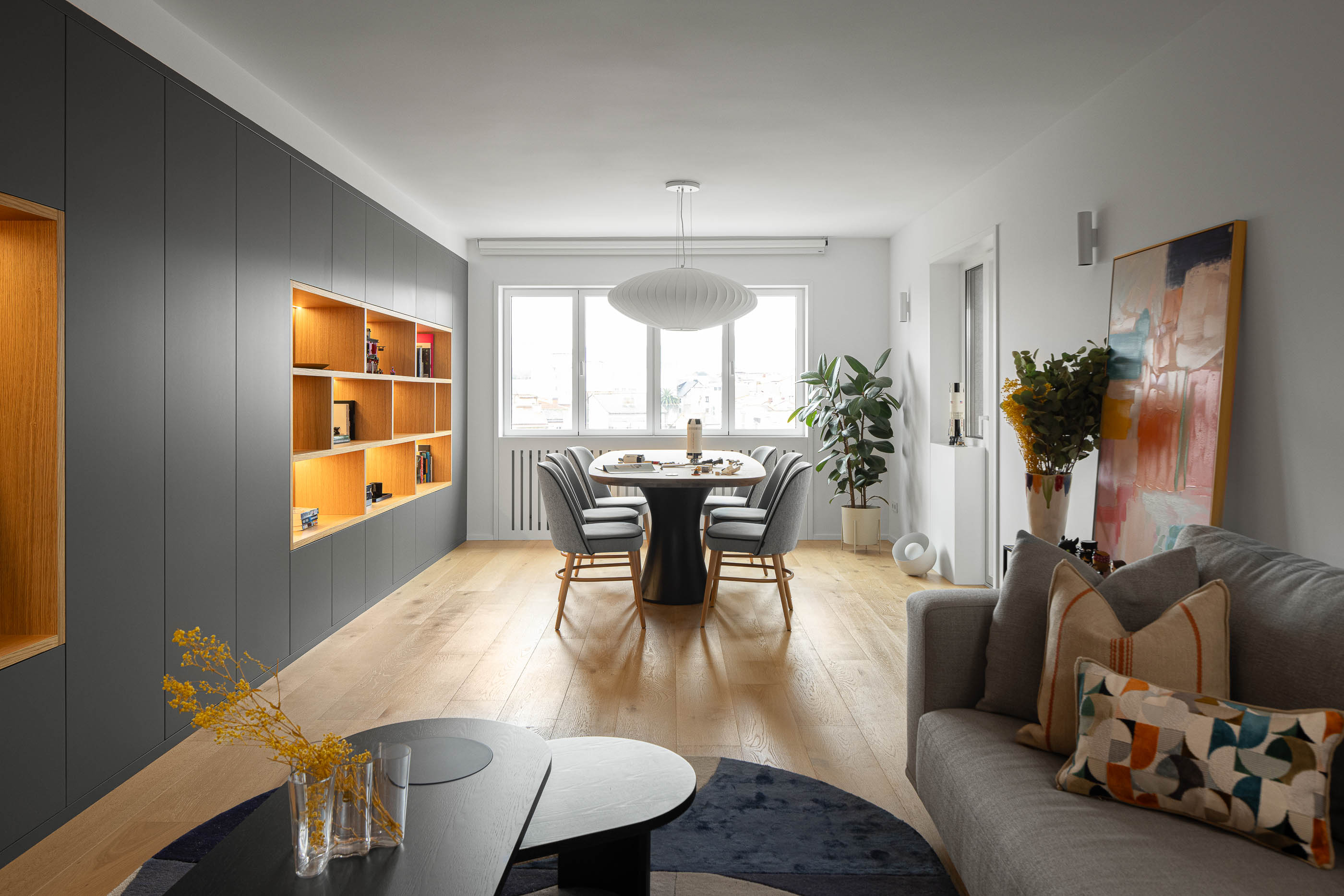 Sala de estar e jantar com sofá cinzento, mesa de centro, alcatifa geométrica e estante embutida. Pavimento em madeira clara. — Reforma apartamento CP em Avilés arquitetura David Olmos Arquitectos em Avilés