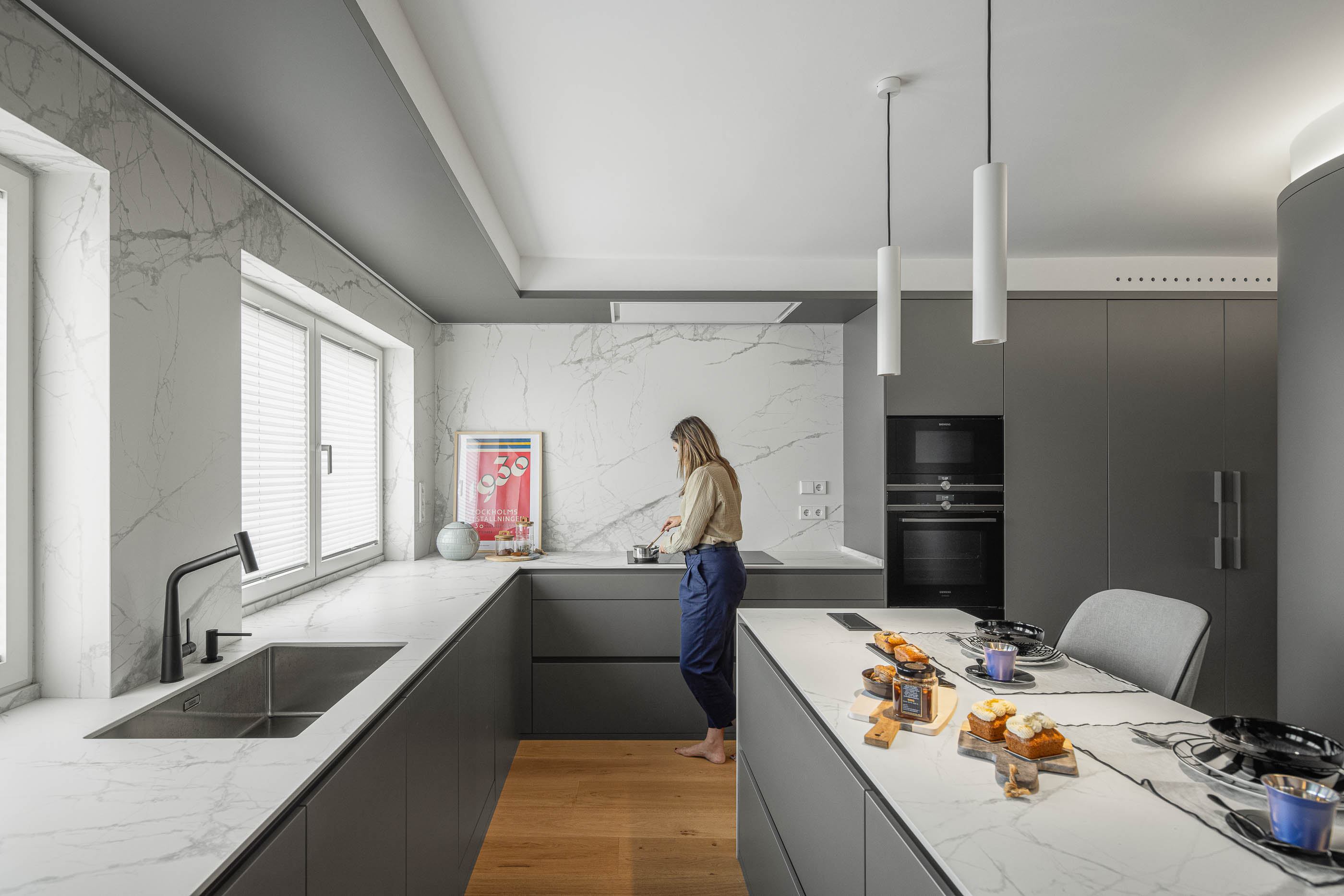 Cozinha com bancada e revestimento em mármore branco, armários cinzentos e pavimento em madeira clara. — Reforma apartamento CP em Avilés arquitetura David Olmos Arquitectos em Avilés