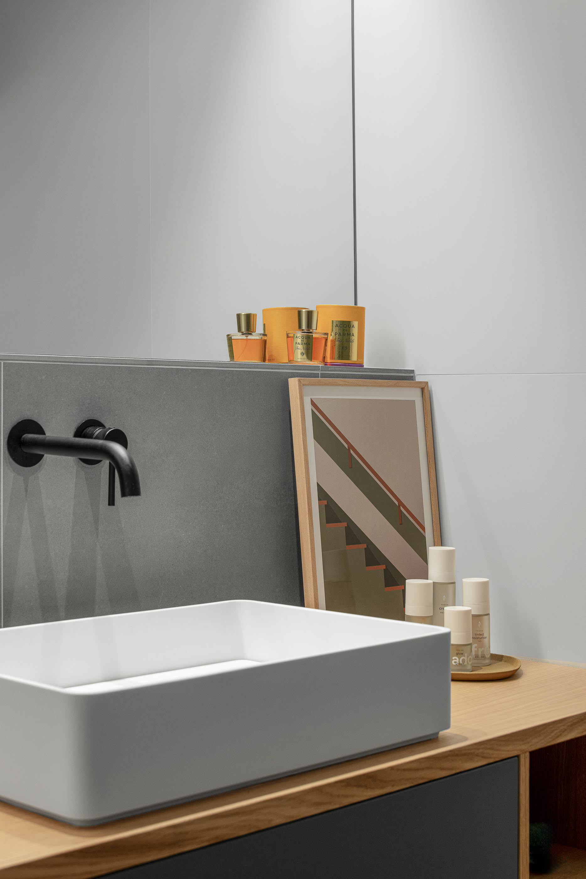 Casa de banho com lavatório branco sobre móvel de madeira, torneira preta e revestimento cinzento. — Reforma apartamento CP em Avilés arquitetura David Olmos Arquitectos em Avilés
