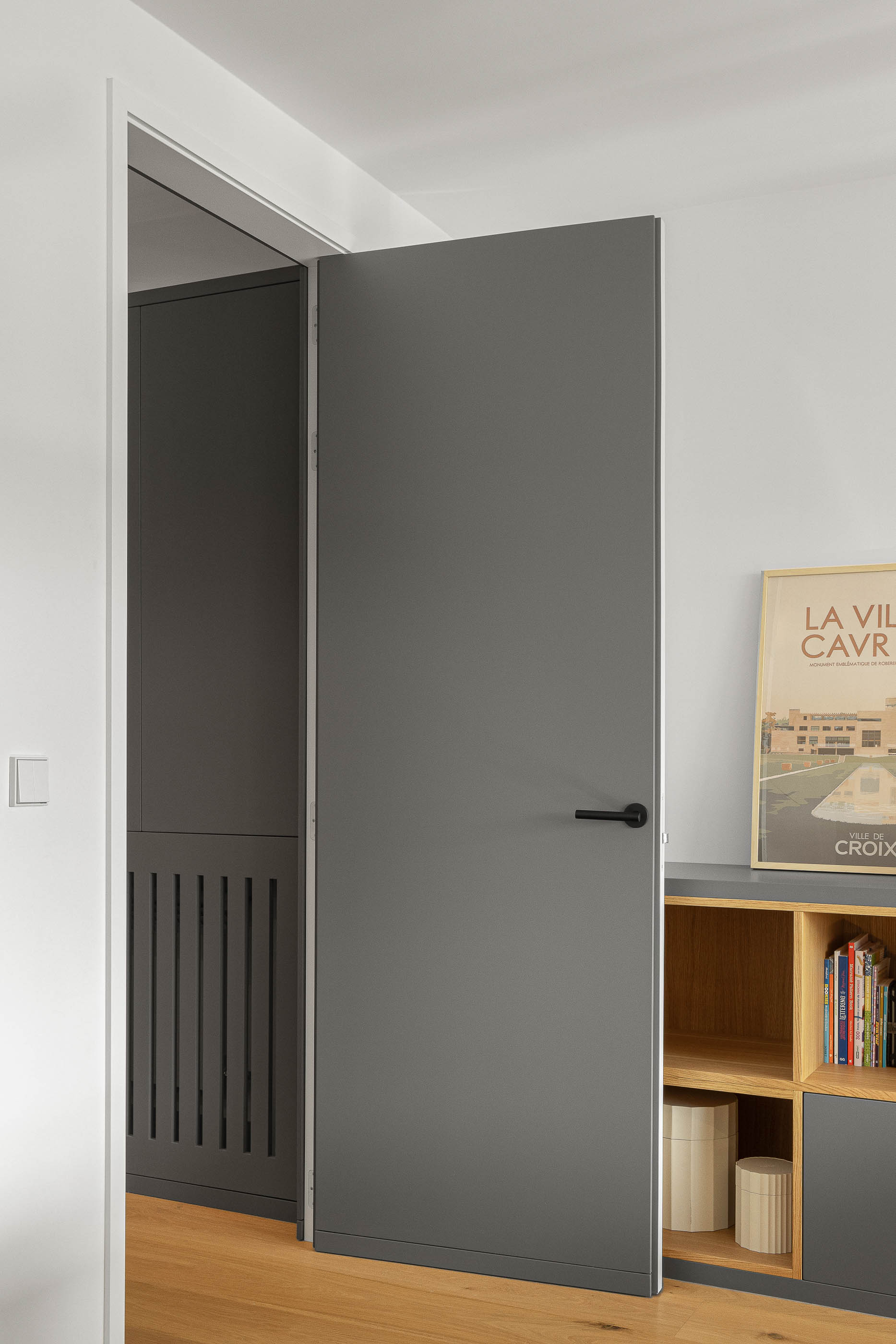 Corredor, detalhe de porta cinzenta aberta para divisão com estante. — Reforma apartamento CP em Avilés arquitetura David Olmos Arquitectos em Avilés