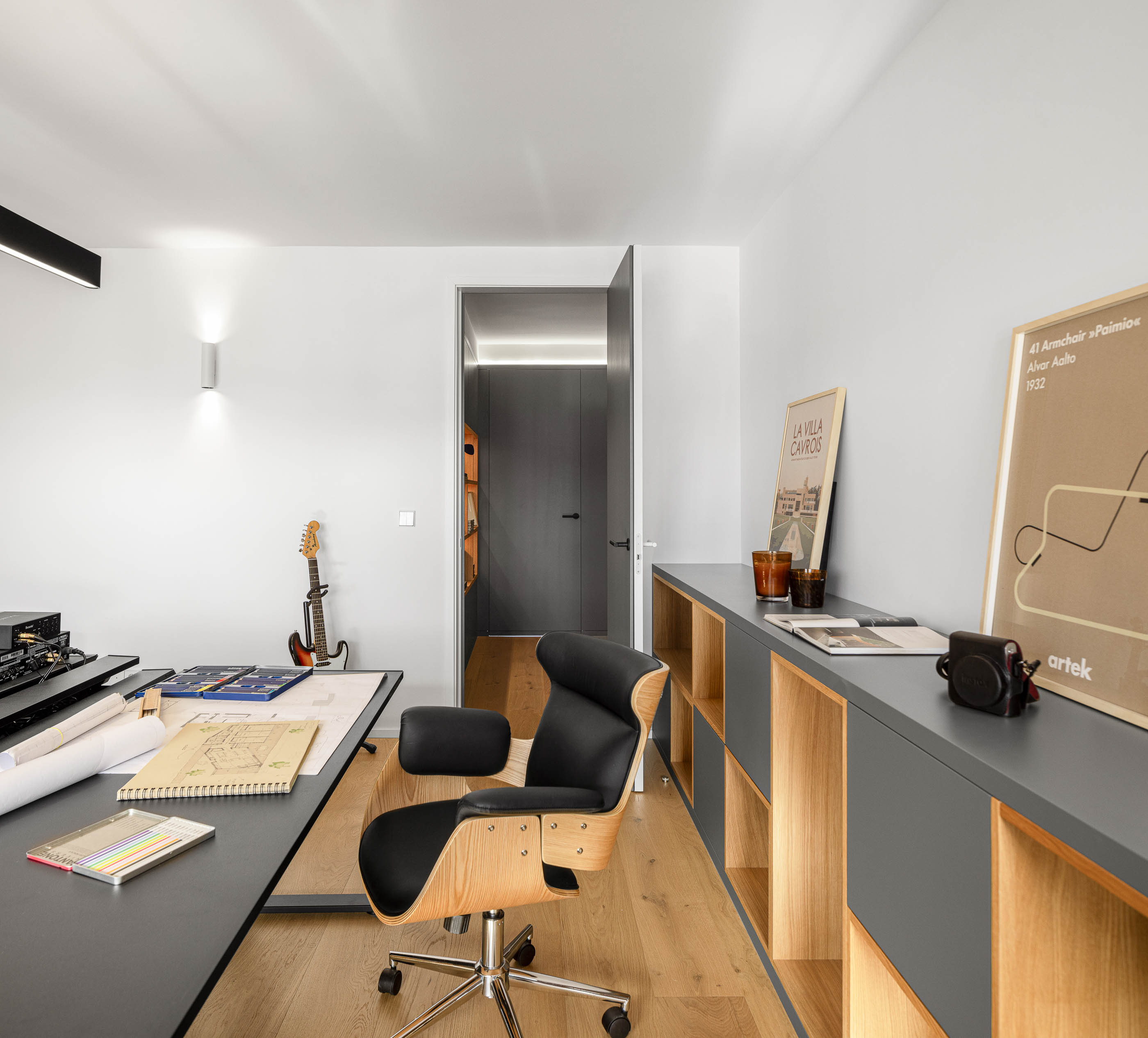 Escritório com secretária preta, cadeira ergonómica e estante com iluminação. Pavimento em madeira clara. — Reforma apartamento CP em Avilés arquitetura David Olmos Arquitectos em Avilés